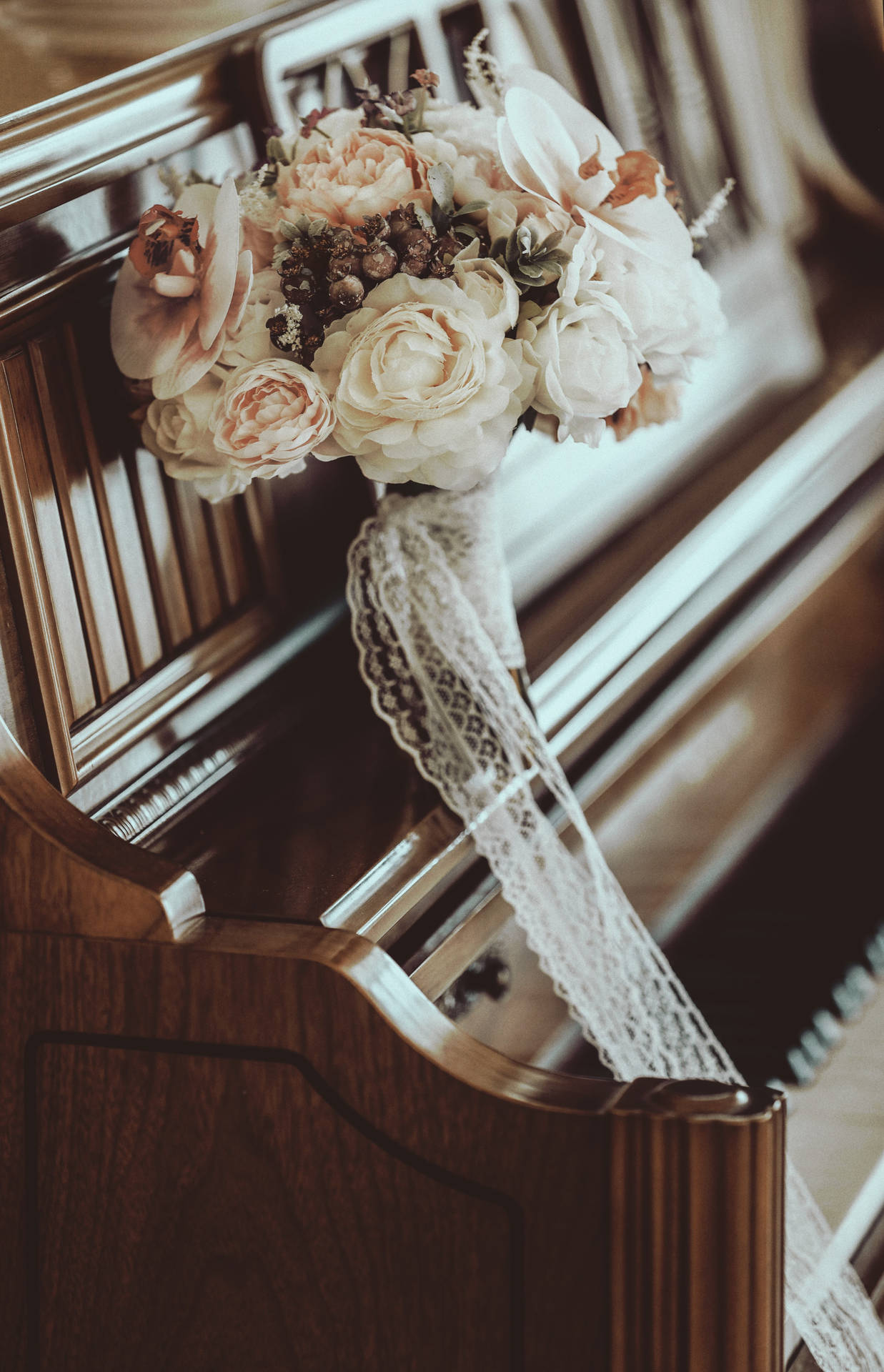 一個帶有蕾絲絲帶的婚禮花束放在木製教堂長椅上。