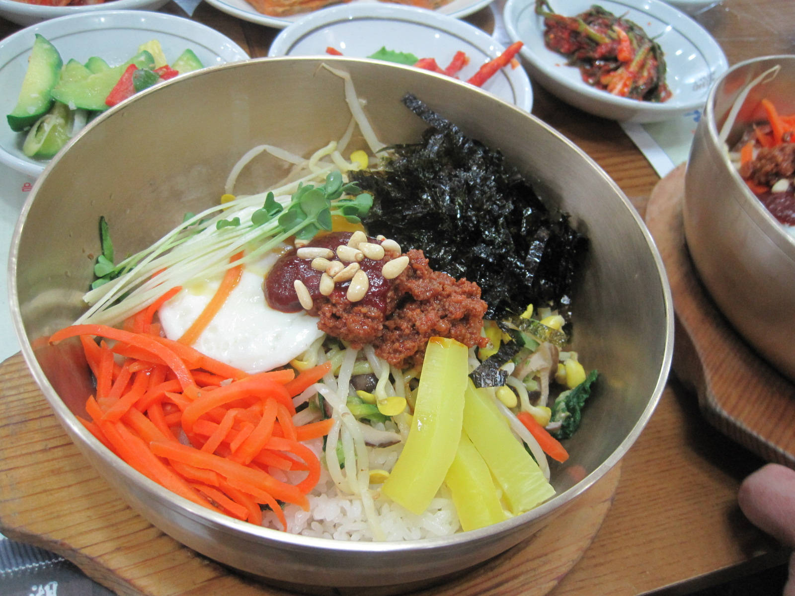 鋼碗盛裝的韓式拌飯 壁紙 — 一個充滿活力的韓國石鍋拌飯碗，裝滿米飯、色彩繽紛的蔬菜和美味配料，放在金屬碗中。