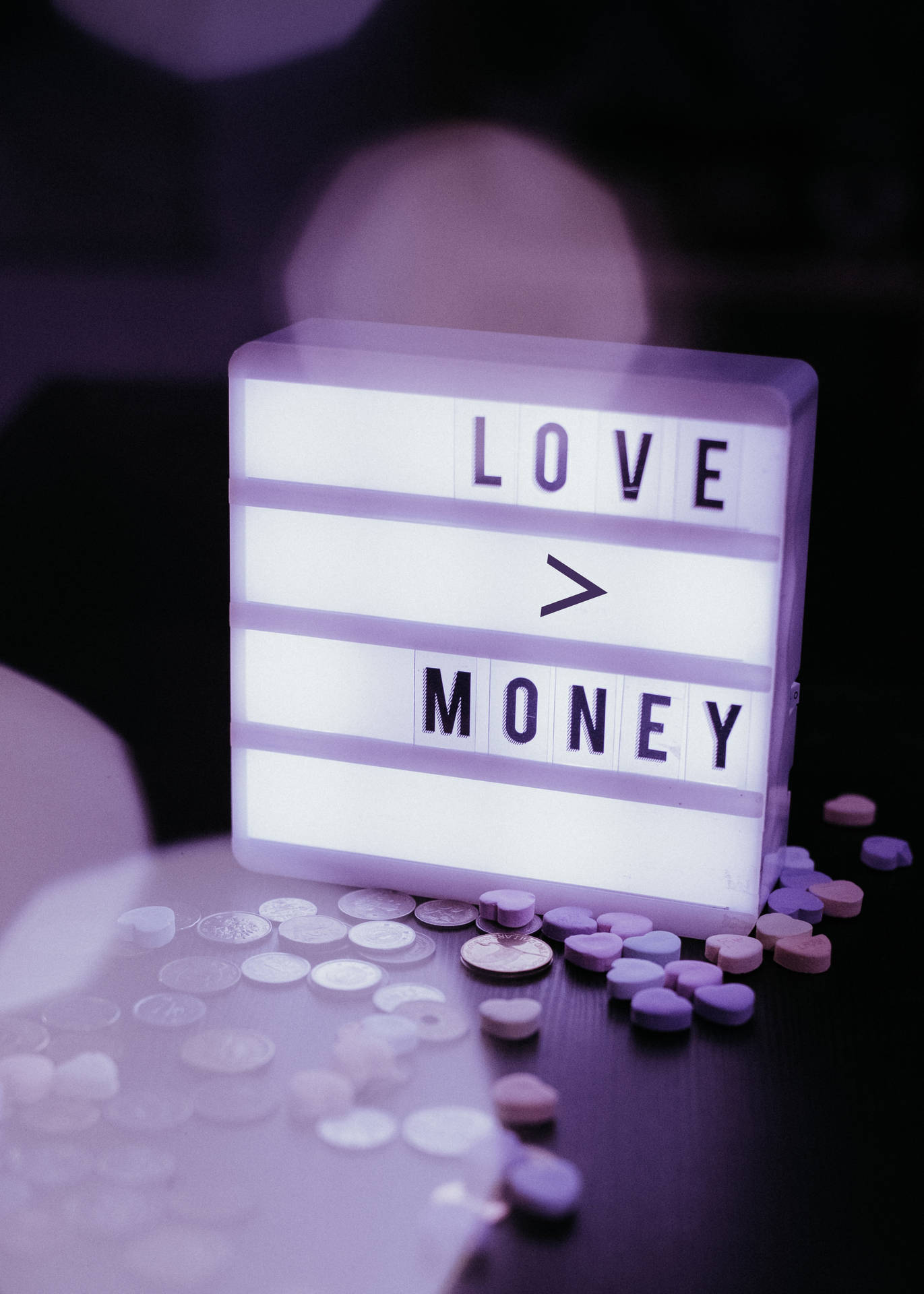 燈箱顯示「LOVE > MONEY」，周圍散落著硬幣和藥丸。
