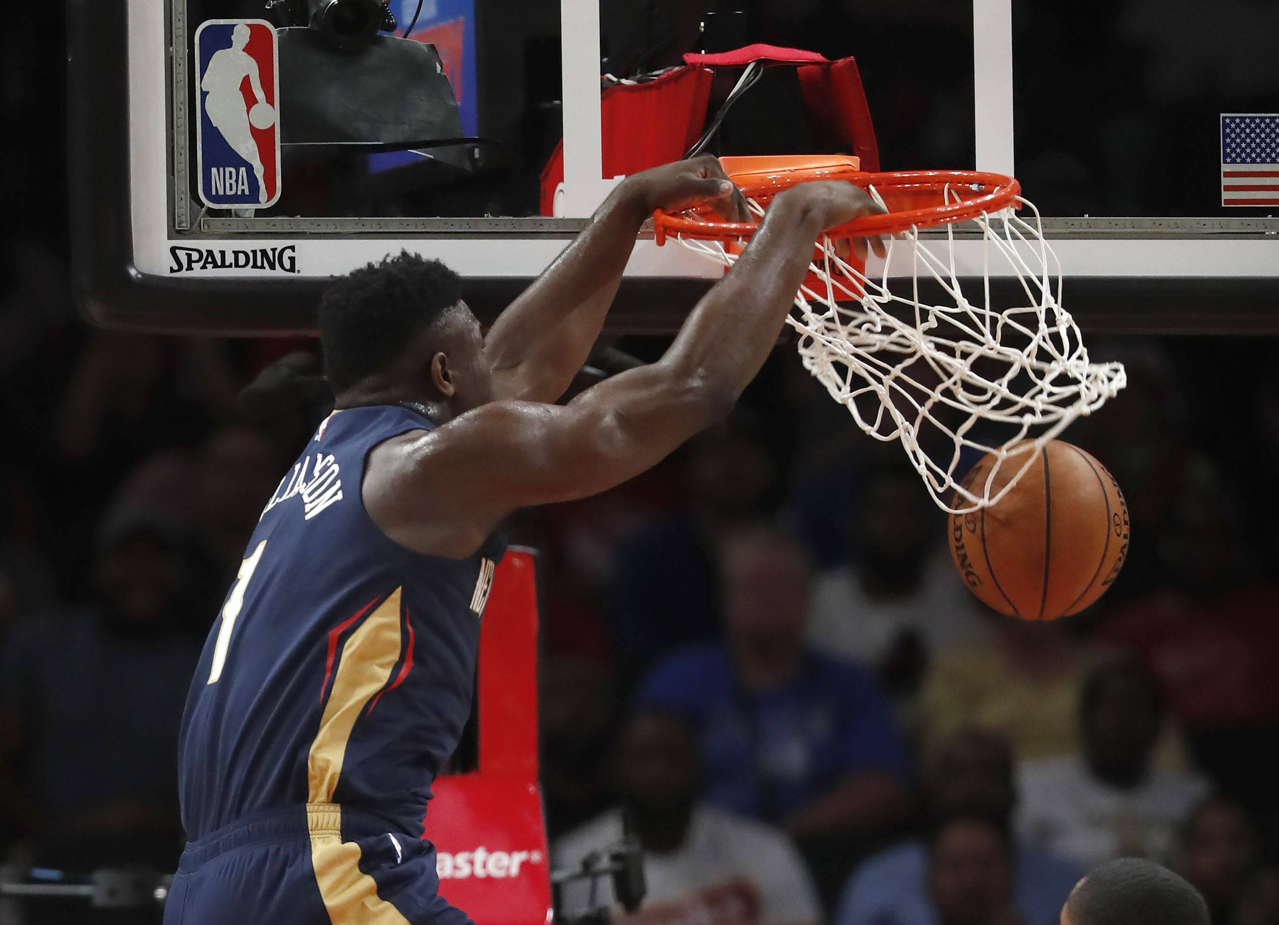 錫安·威廉森 灌籃 壁紙 — 一名身穿藍金色球衣的籃球運動員在NBA比賽中，於場館燈光下強力入樽。
