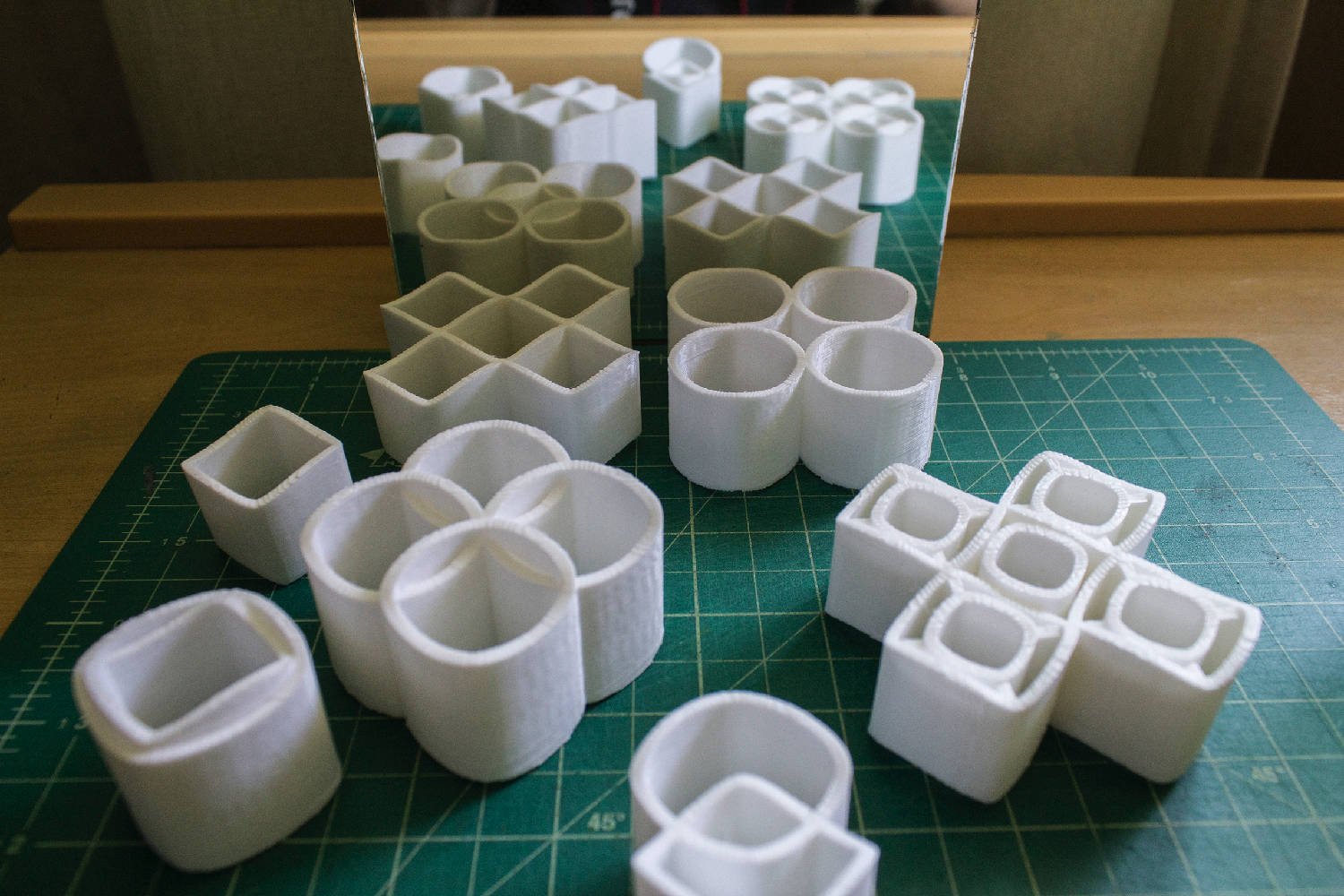 白色3D打印幾何形狀在帶有網格線的綠色切割墊上。