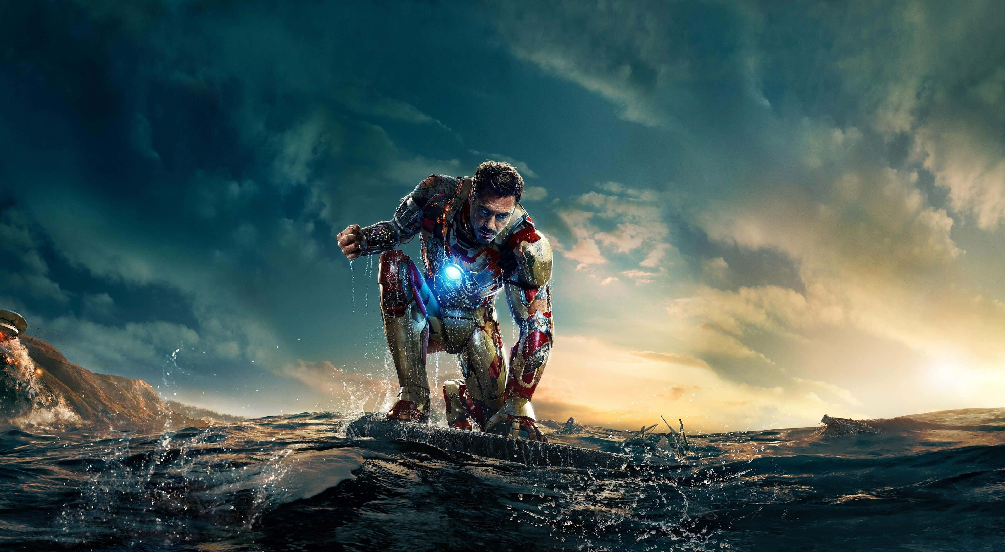 4K Marvel 壁紙 桌布 壁紙 — 鐵甲奇俠在波濤洶湧的海水中蹲伏，背景是戲劇性的日落天空，胸口反應爐閃閃發光。
