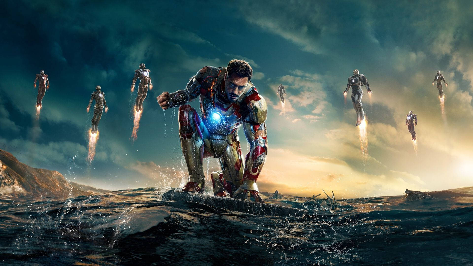 鋼鐵人 桌布 壁紙 — 鐵甲奇俠跪喺岩石海岸上，多套戰甲喺佢上方盤旋，背景係戲劇性嘅日落天空。