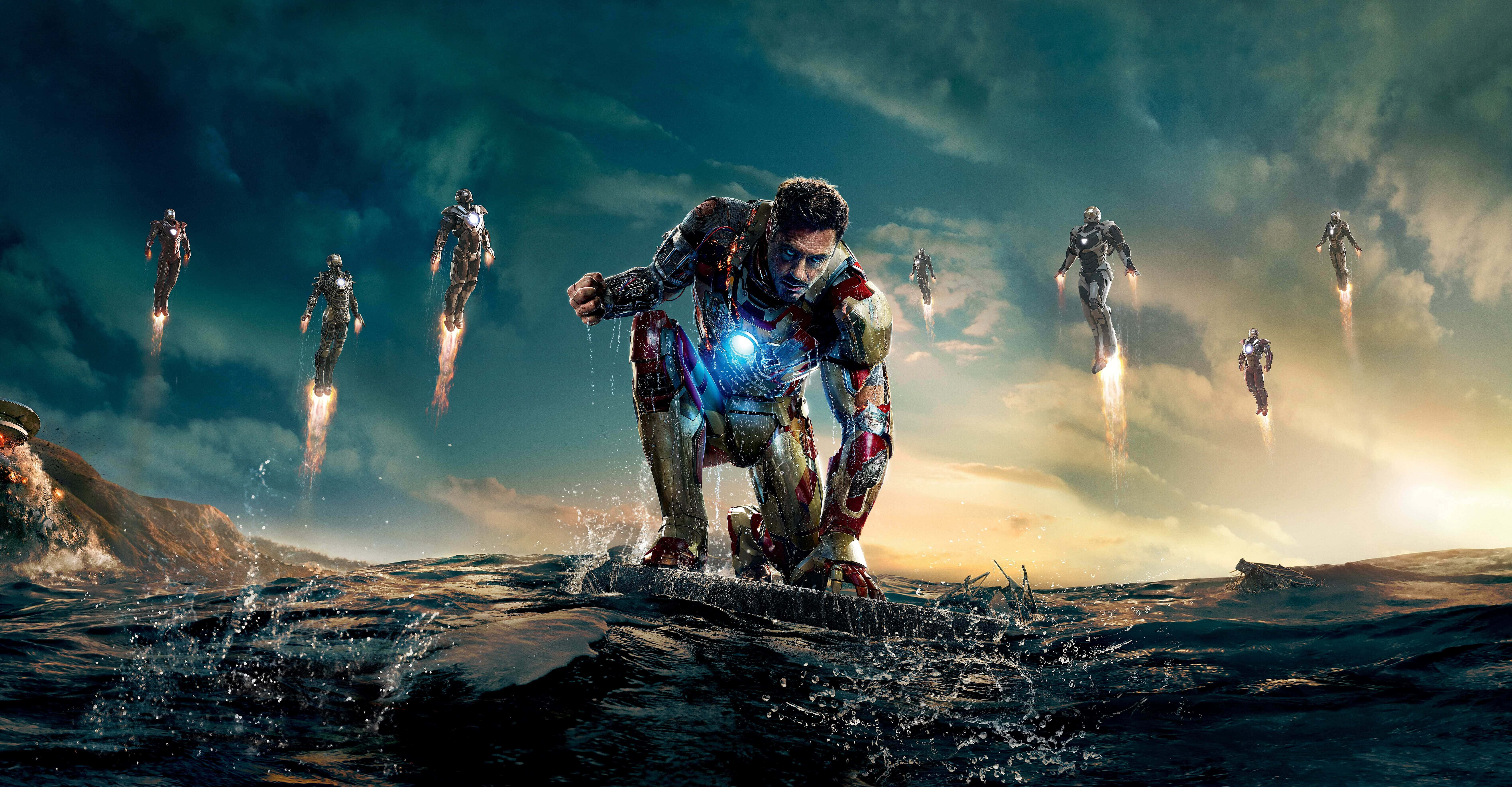 Iron Man Movies 桌布 壁紙 — 鐵甲奇俠跪在海浪中，多個鐵甲奇俠戰衣在戲劇性的日落天空背景下飛過頭頂。