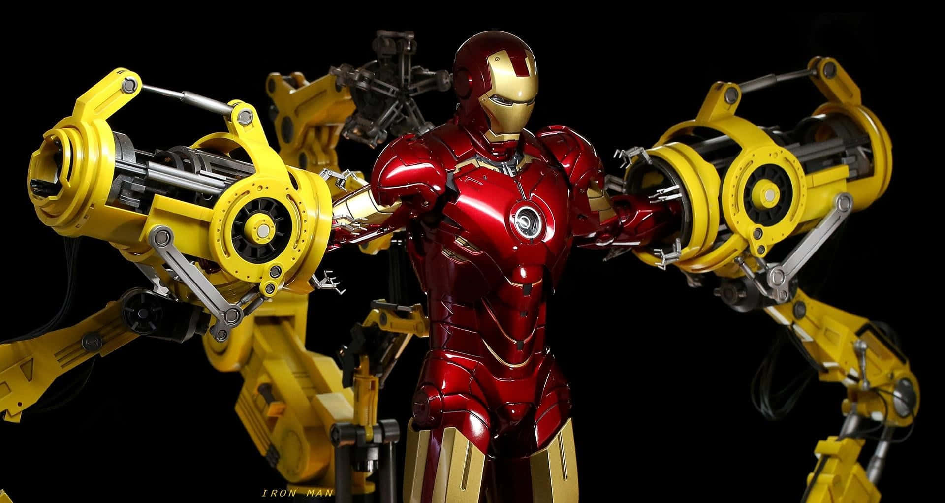 Iron Man Suit 桌布 壁紙 — 鐵甲奇俠身穿紅色和金色裝甲，居中站立，兩側伸出巨大的黃色機械臂，背景為黑色。