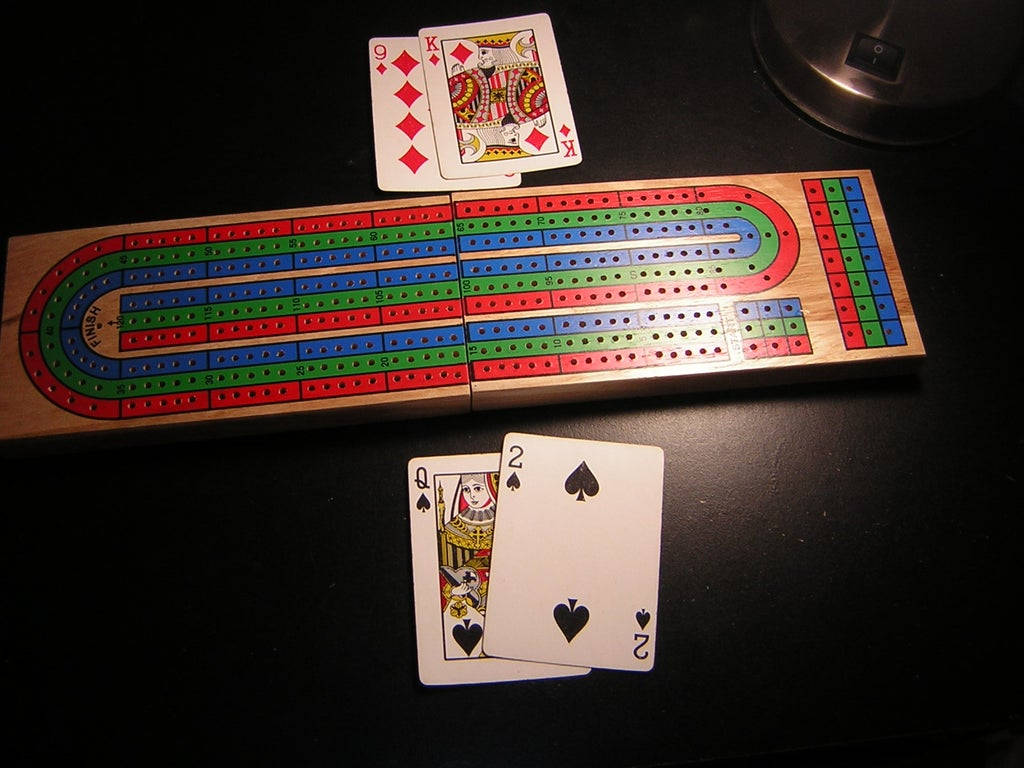 Cribbage 板同啤牌喺黑暗嘅枱上。