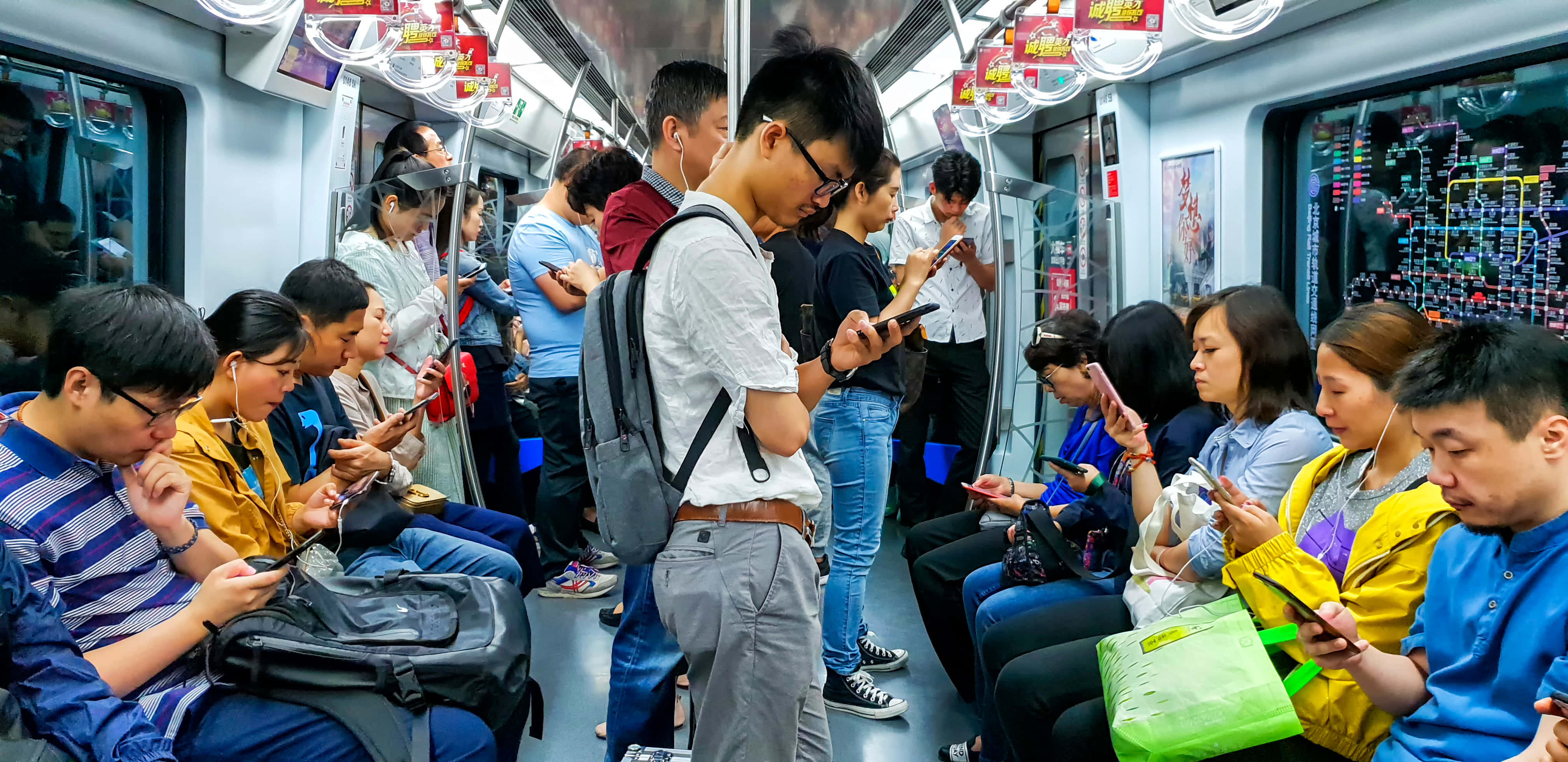 長城壯麗景色 壁紙 — 繁忙時間擠滿通勤者的地鐵車廂，所有人都全神貫注於智能手機。