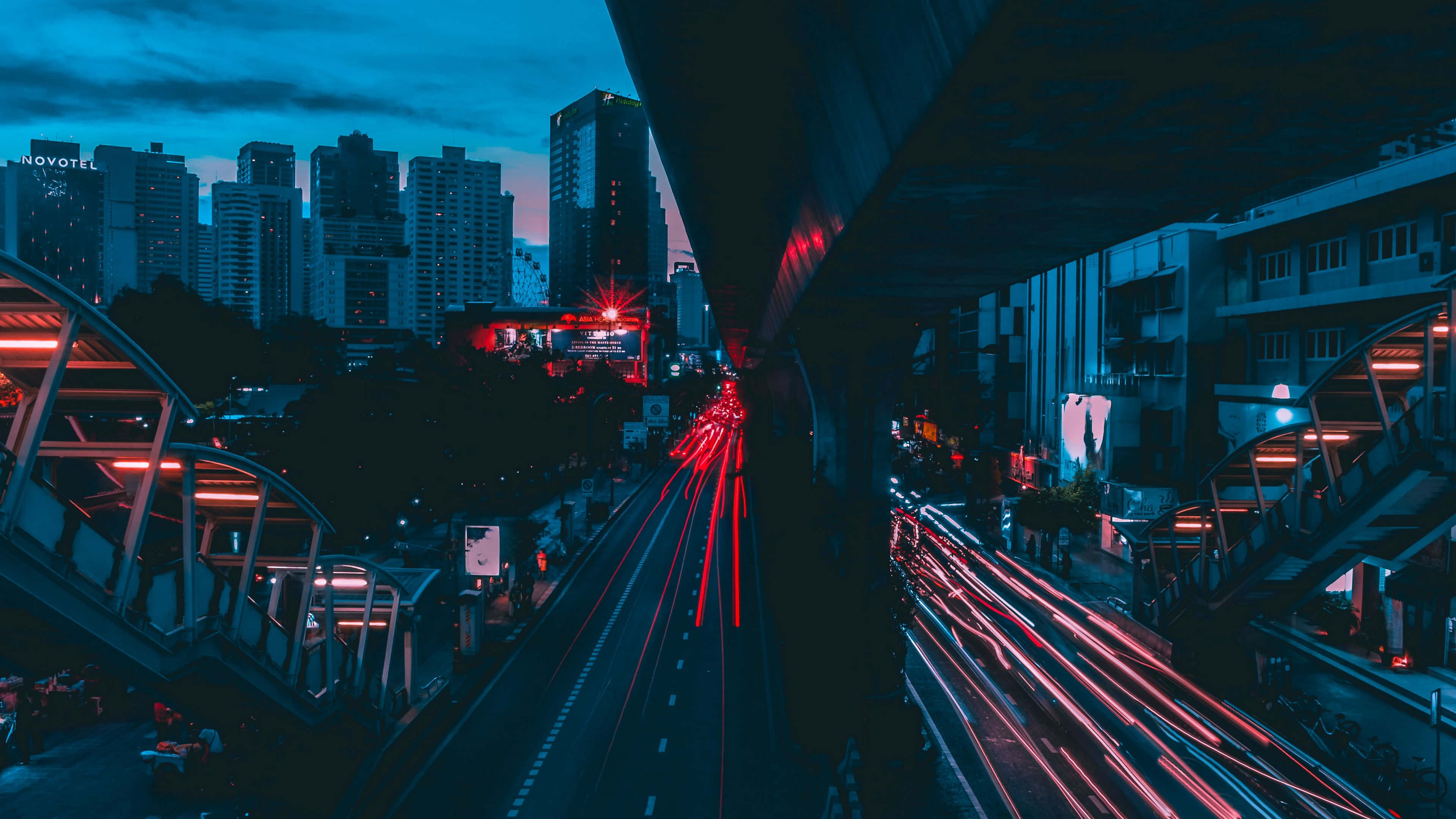Dark Crossroad 桌布 壁紙 — 長時間曝光拍攝捕捉到在暮色城市天際線下，天橋下流動的交通所產生的鮮紅色光軌。