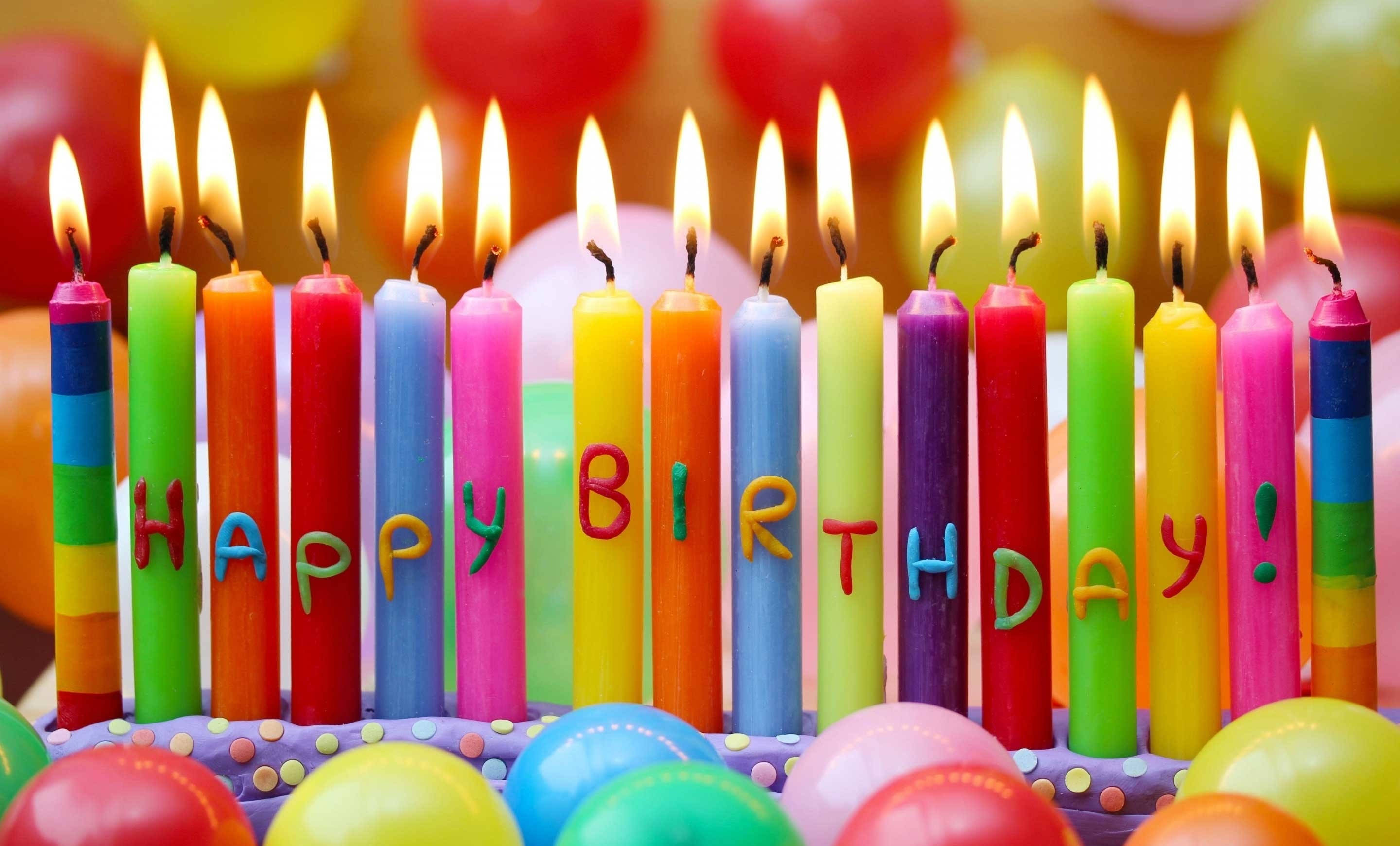 長條彩色生日蛋糕蠟燭 壁紙 — 生日蛋糕的特寫，彩色蠟燭拼出「HAPPY BIRTHDAY」，點燃的火焰被氣球環繞。