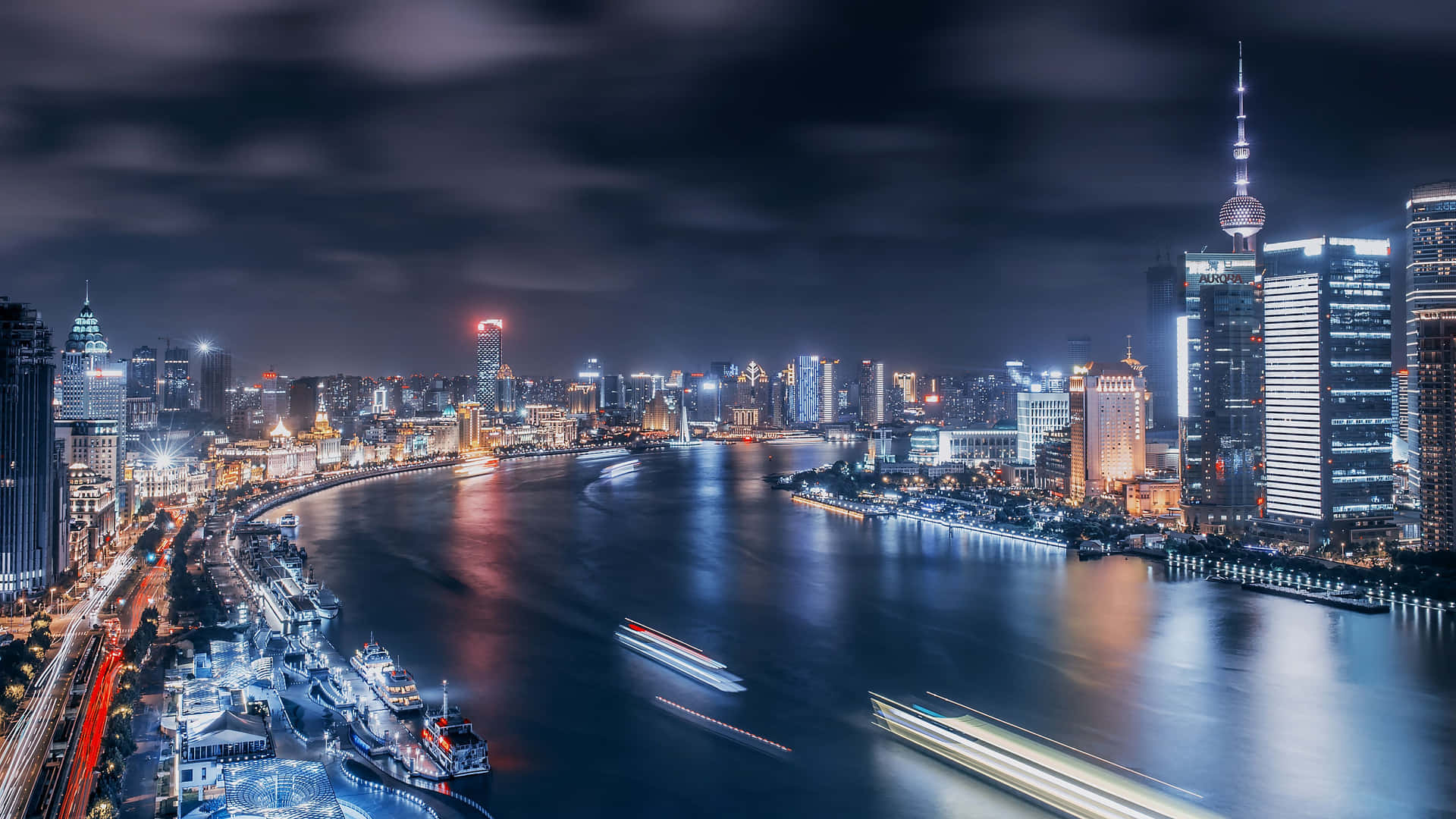 夜間城市天際線，河上有發光的建築物和船隻。