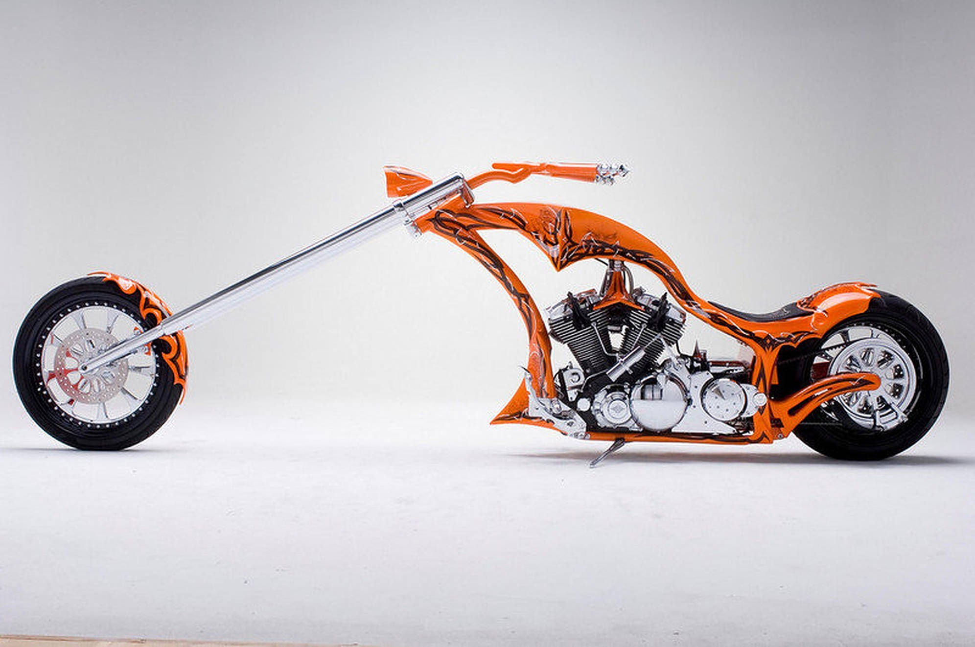 長身橙色哈雷摩托車 壁紙 — 一架訂製的橙色和鉻色chopper電單車，配有長把手和火焰貼花，在純白色工作室背景前擺好姿勢。