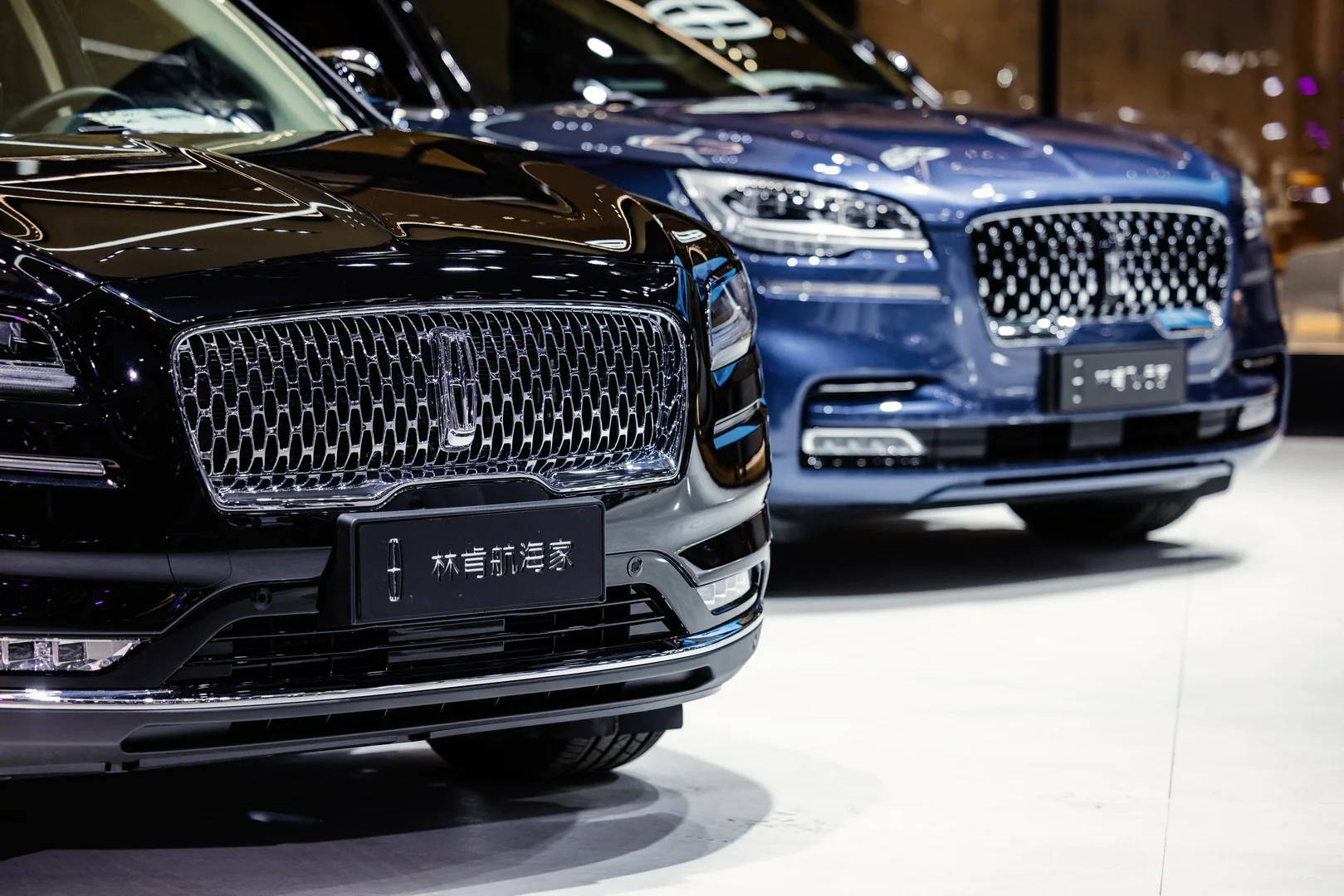 閃亮林肯Nautilus與Aviator豪華轎車 壁紙 — 兩輛豪華SUV，配備鍍鉻格柵和時尚頭燈，在明亮的展廳燈光下展示。