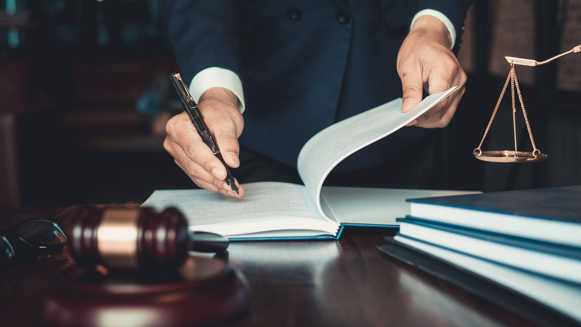 律師在桌上放著法槌和正義天平簽署法律文件。