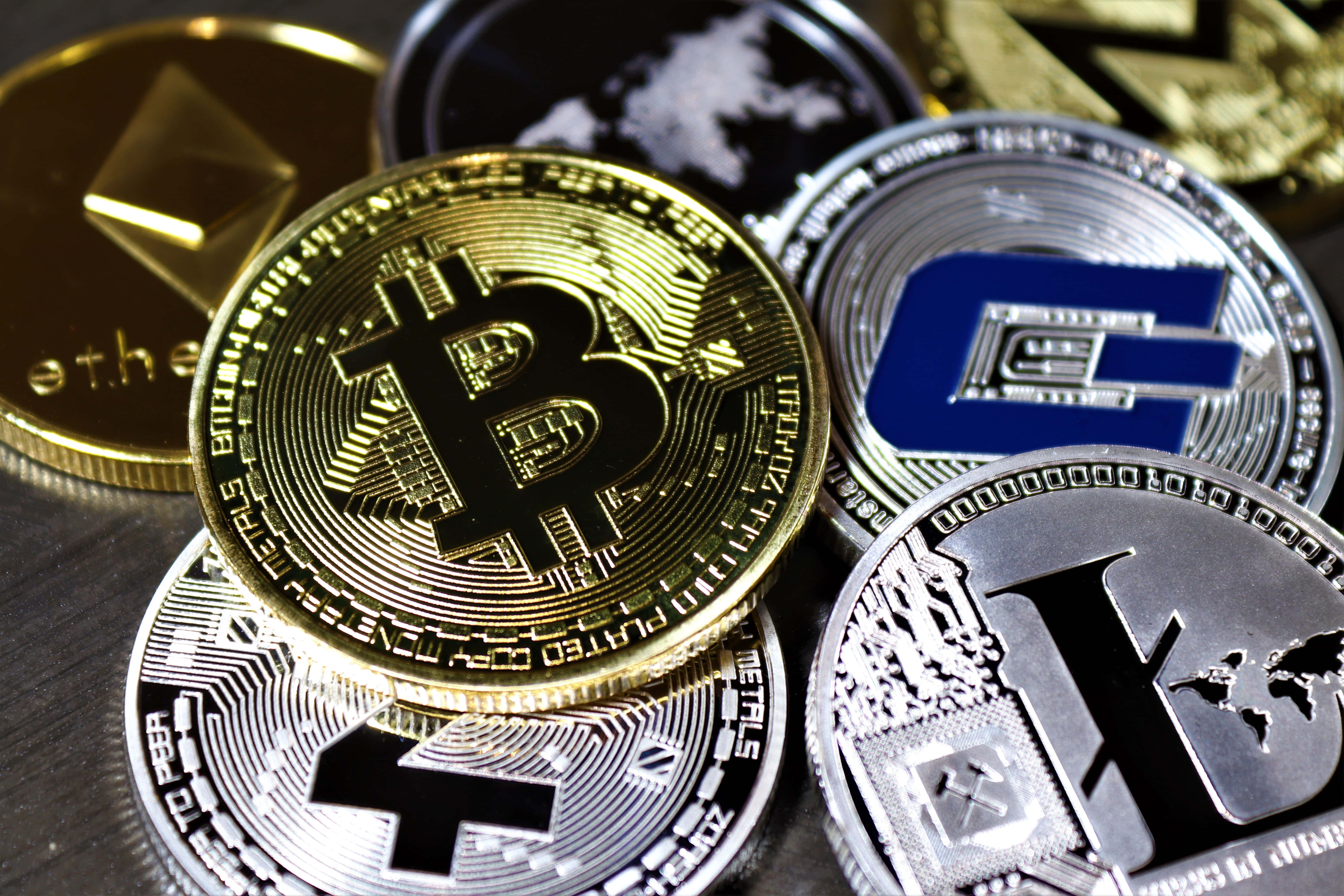 Mining 桌布 壁紙 — 閃亮物理加密貨幣硬幣的特寫，包括比特幣、以太坊和萊特幣，排列在黑暗表面上。