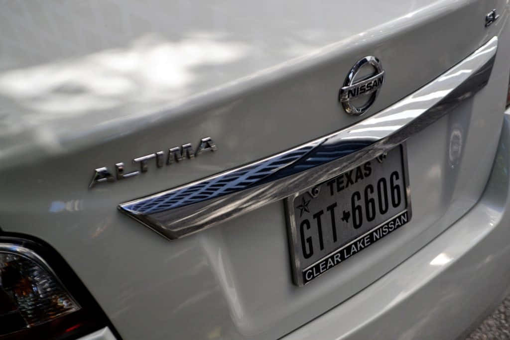 閃亮白色德州車牌 壁紙 — 銀色日產Altima後備箱特寫，帶有德州車牌和經銷商品牌標識。