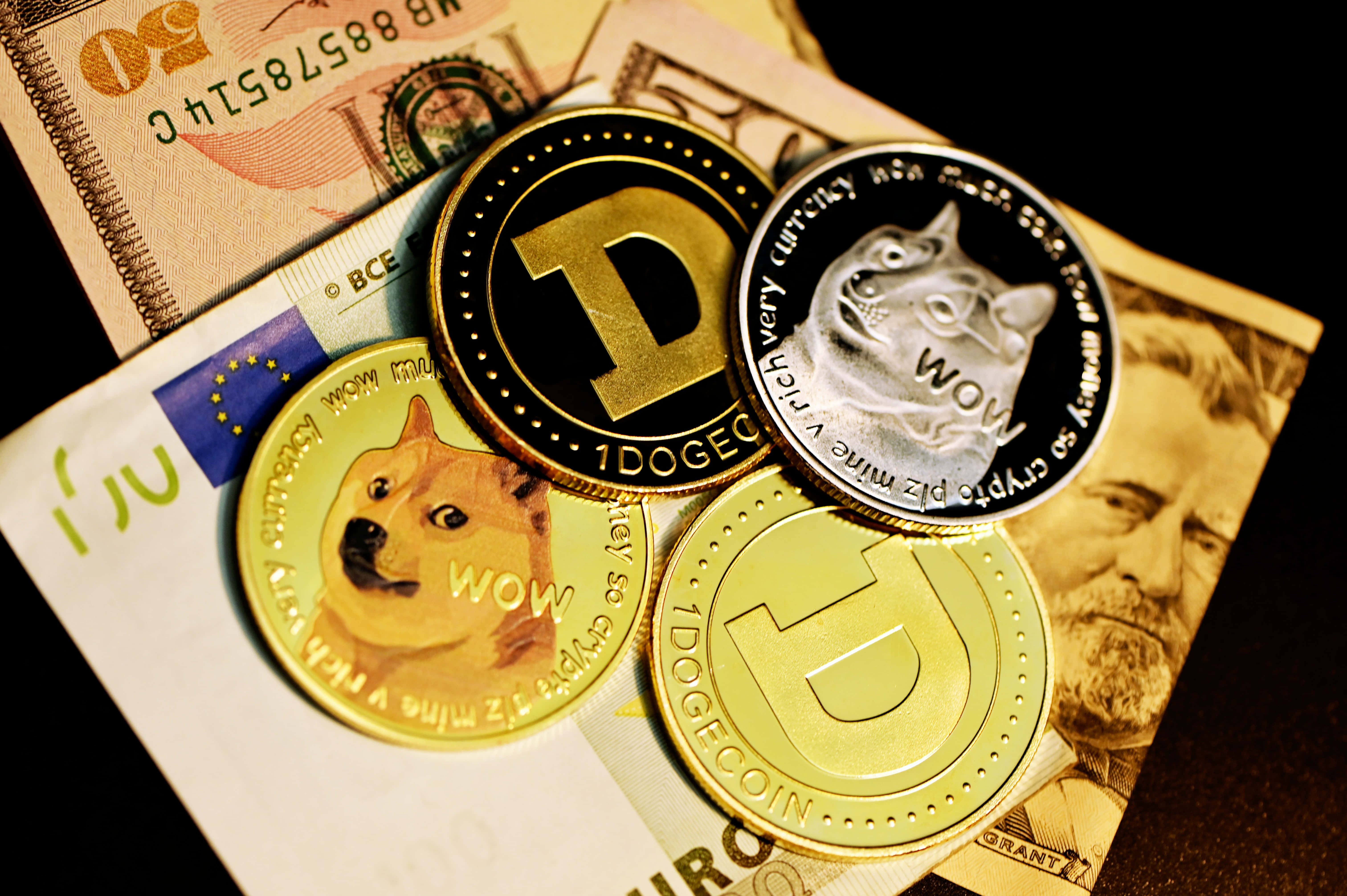 Dogecoin 桌布 壁紙 — 閃亮的狗狗幣代幣放在散落的全球紙幣堆上，在戲劇性的燈光下。