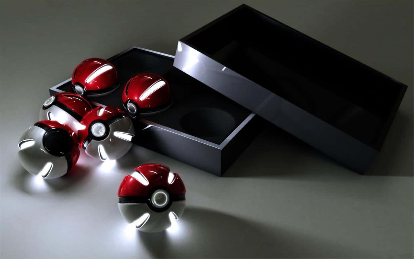 Pokemon Toys 桌布 壁紙 — 閃亮的紅色和銀色精靈球帶有發光燈光，從一個時尚的黑色盒子中溢出，放在極簡灰色表面上。