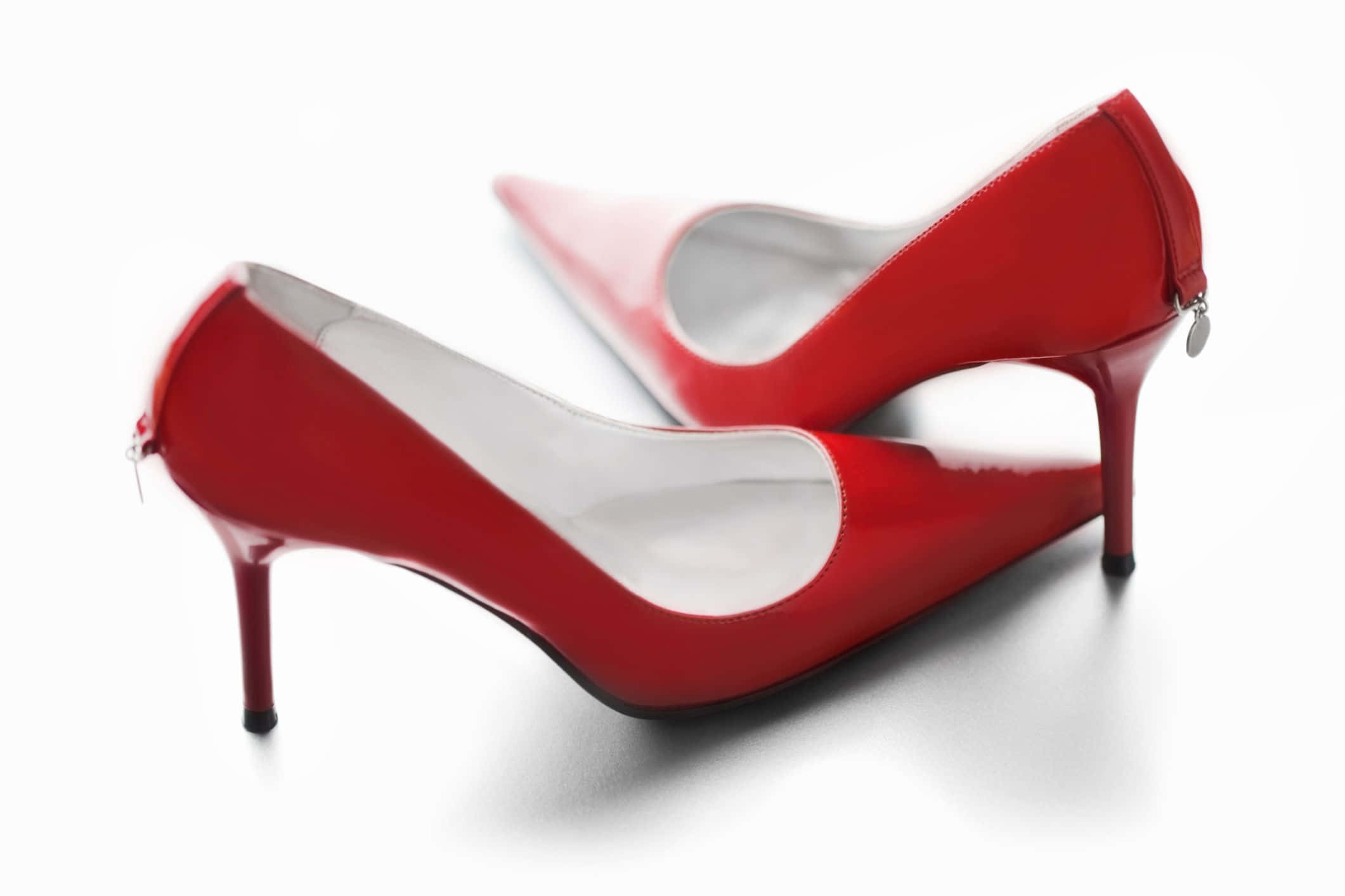 Red High Heels 桌布 壁紙 — 閃亮的紅色漆皮高跟鞋，白色內裡和細鞋跟，放置在潔白的表面上。