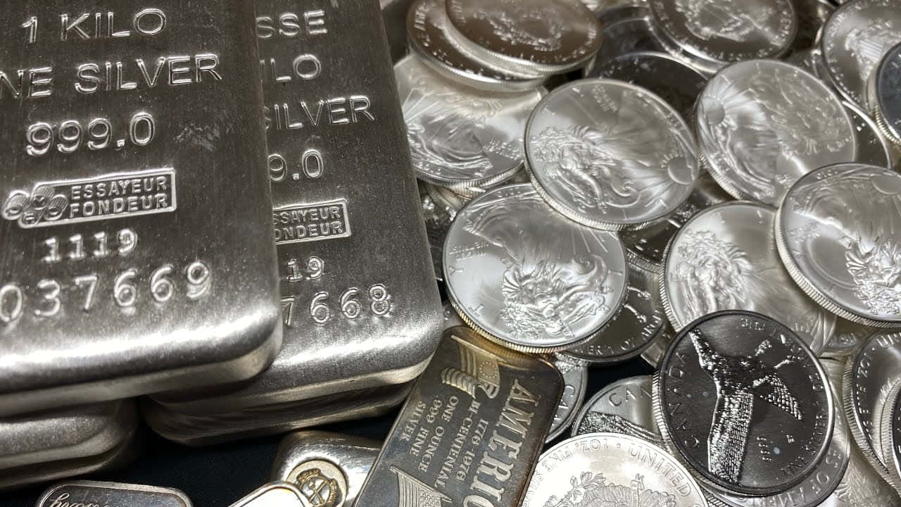 銀色 桌布 壁紙 — 閃亮銀條和銀幣堆疊在一起的近距離特寫，帶有雕刻細節和反光表面。