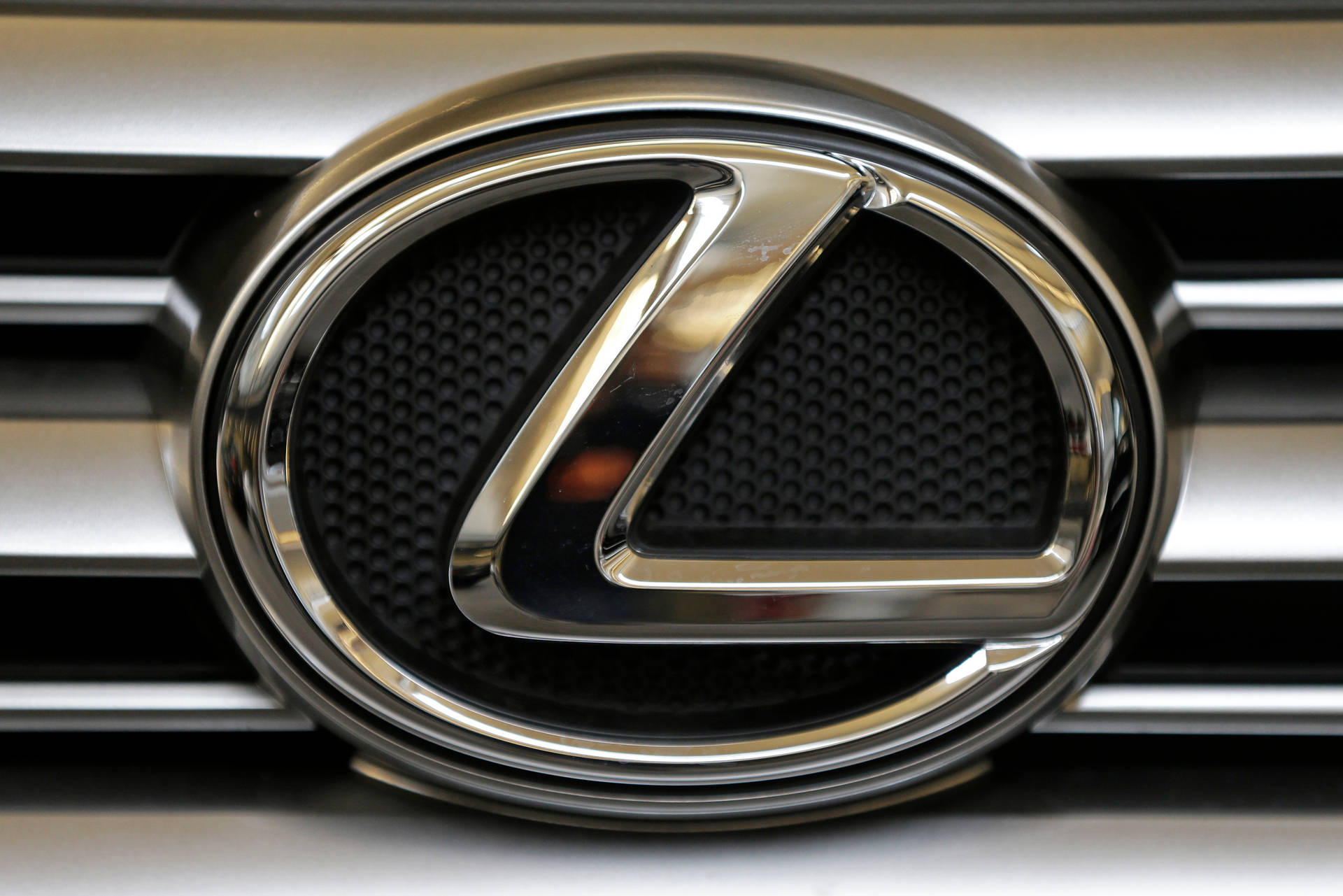 黑色穿孔背景的汽車格柵上的鍍鉻 Lexus 標誌。