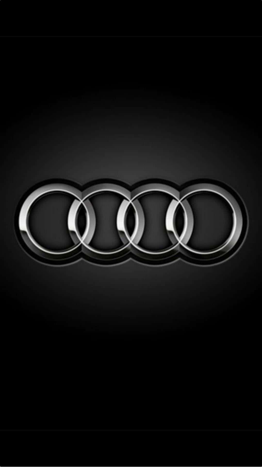 Car Logo 桌布 壁紙 — 閃亮鍍鉻奧迪四環標誌居中於漸變黑色背景上，帶有微妙燈光效果。