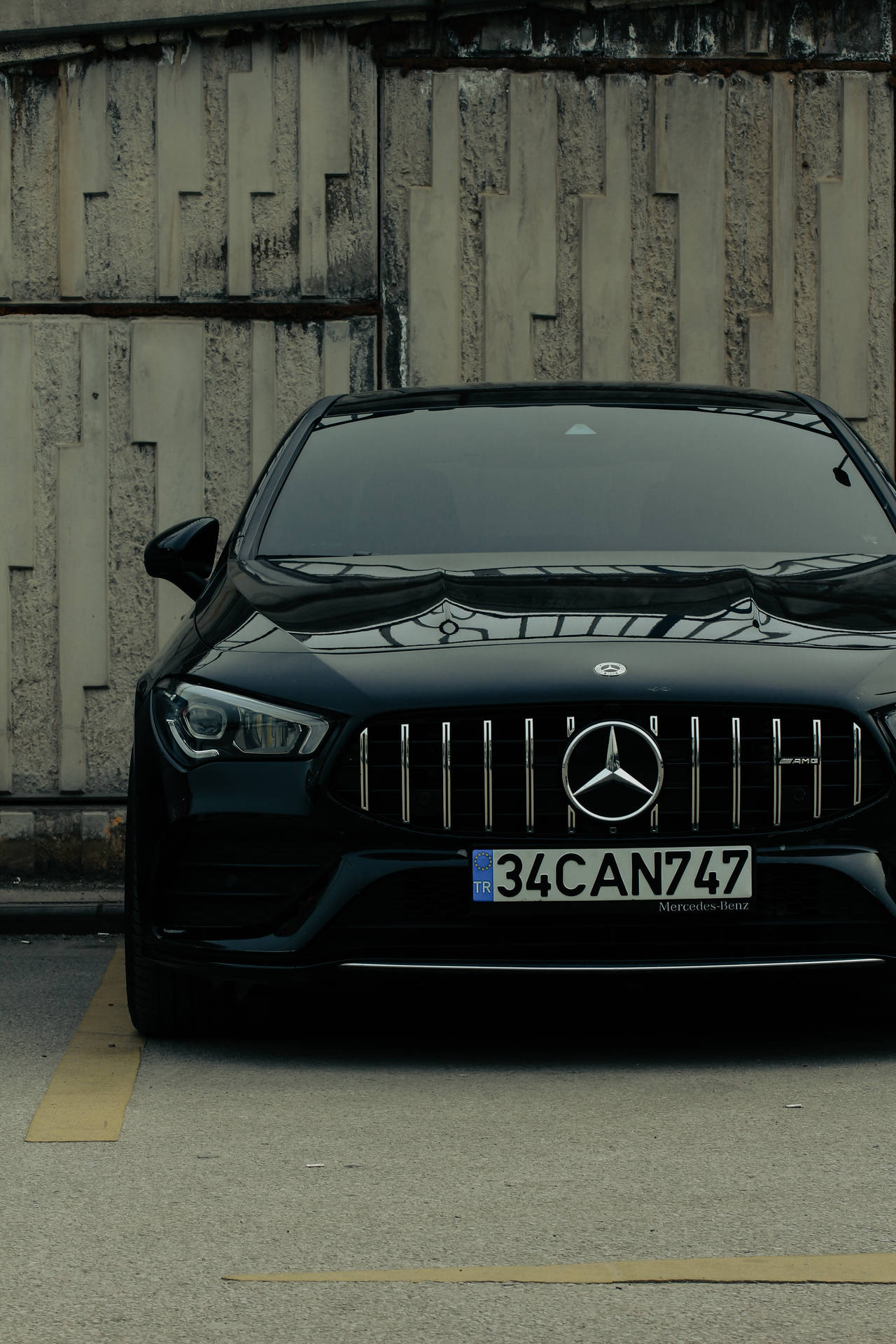 黑色Mercedes-AMG靠著風化的混凝土牆停放。