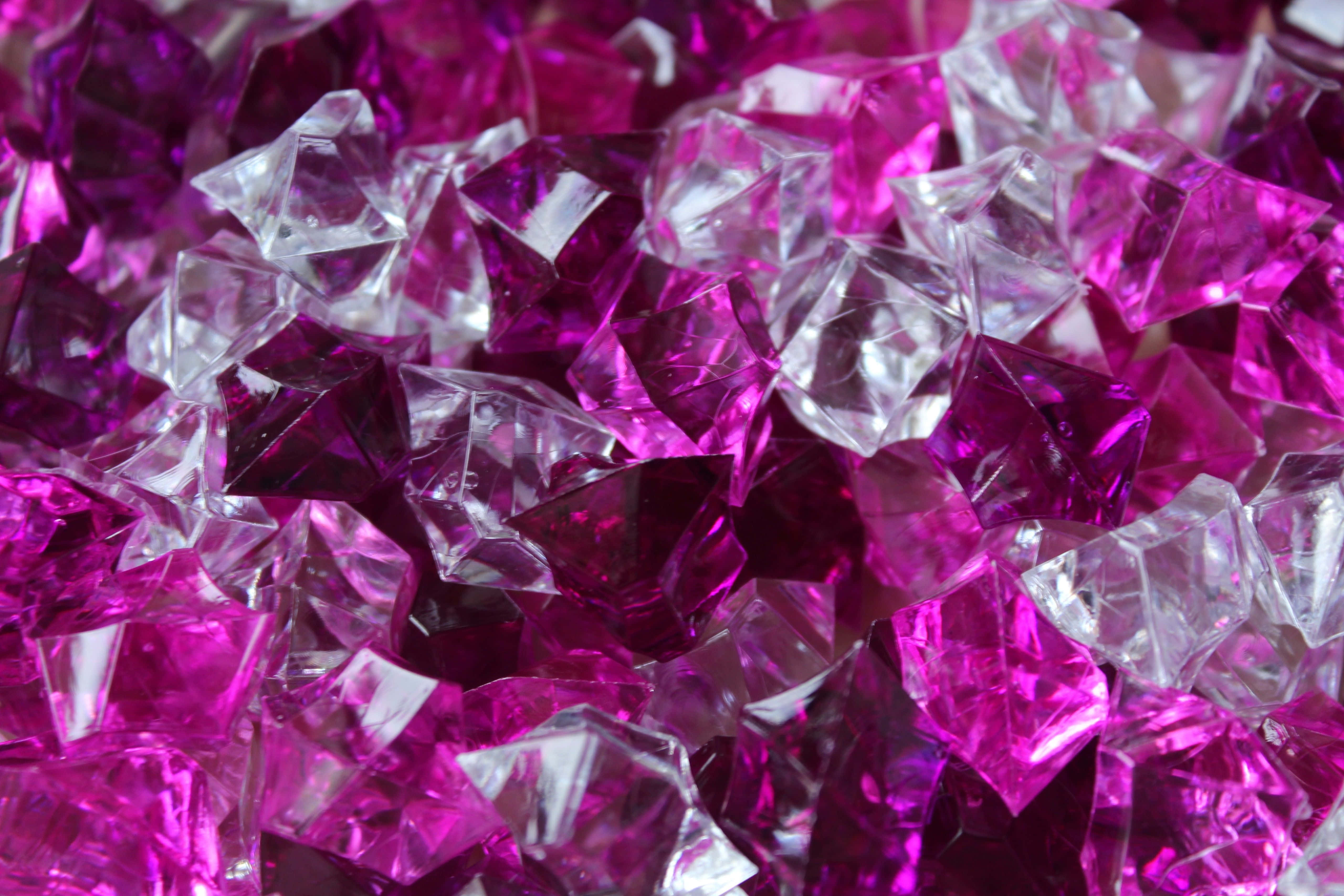 Pink Crystal Quartz 桌布 壁紙 — 閃爍的洋紅色和透明刻面寶石堆疊在一起的近距離特寫，捕捉光線並產生銳利反射。