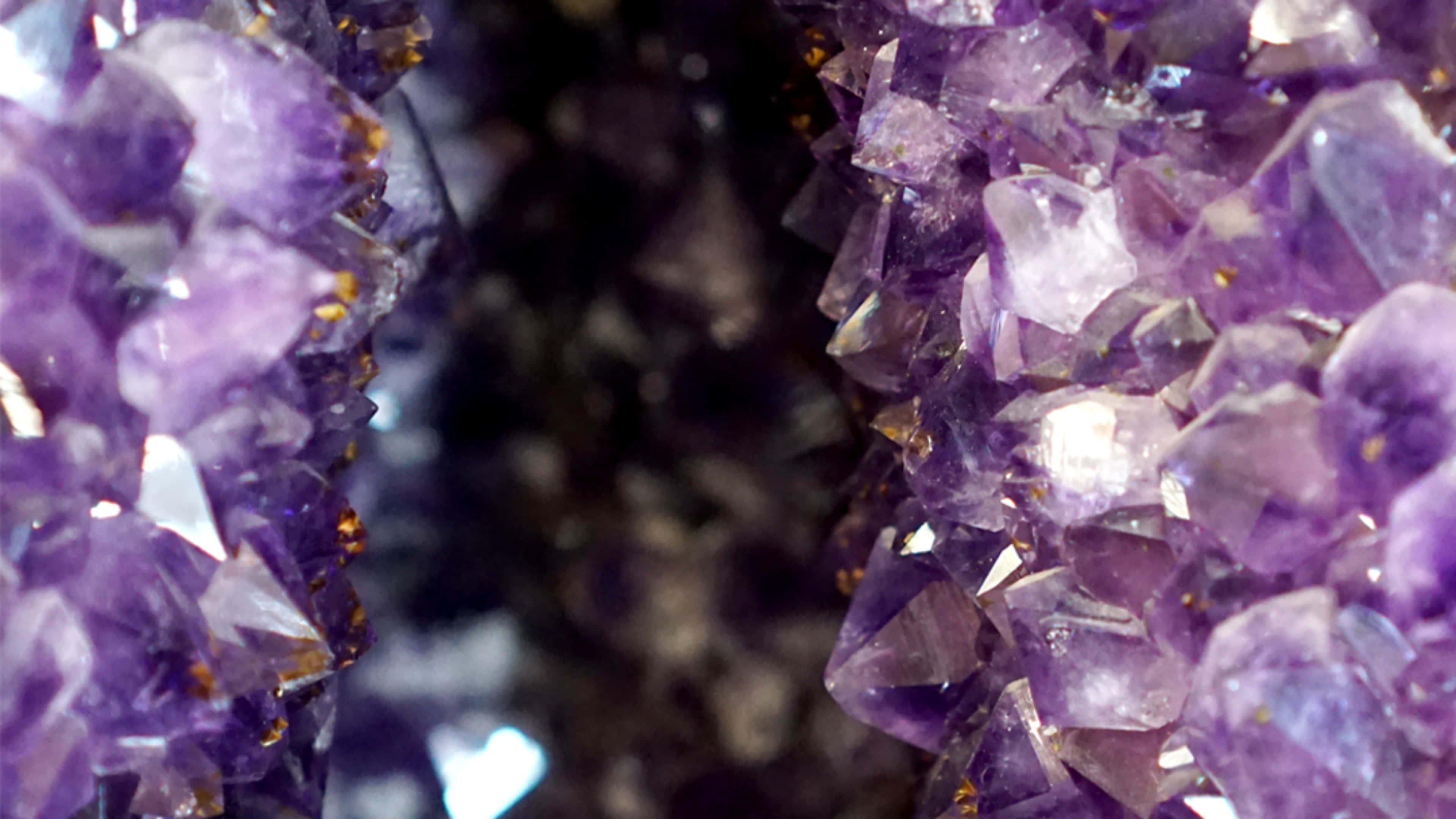 Amethyst 桌布 壁紙 — 閃爍紫色紫水晶晶體的近距離特寫，形成密集簇狀，具有銳利刻面和金色內含物。