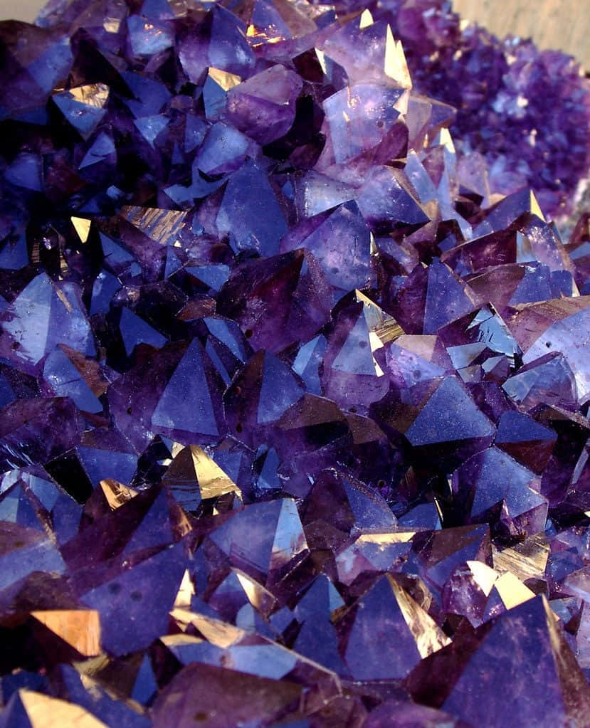Amethyst 桌布 壁紙 — 閃爍紫色紫水晶晶體的近距離特寫，具有銳利的刻面，捕捉金色光線。