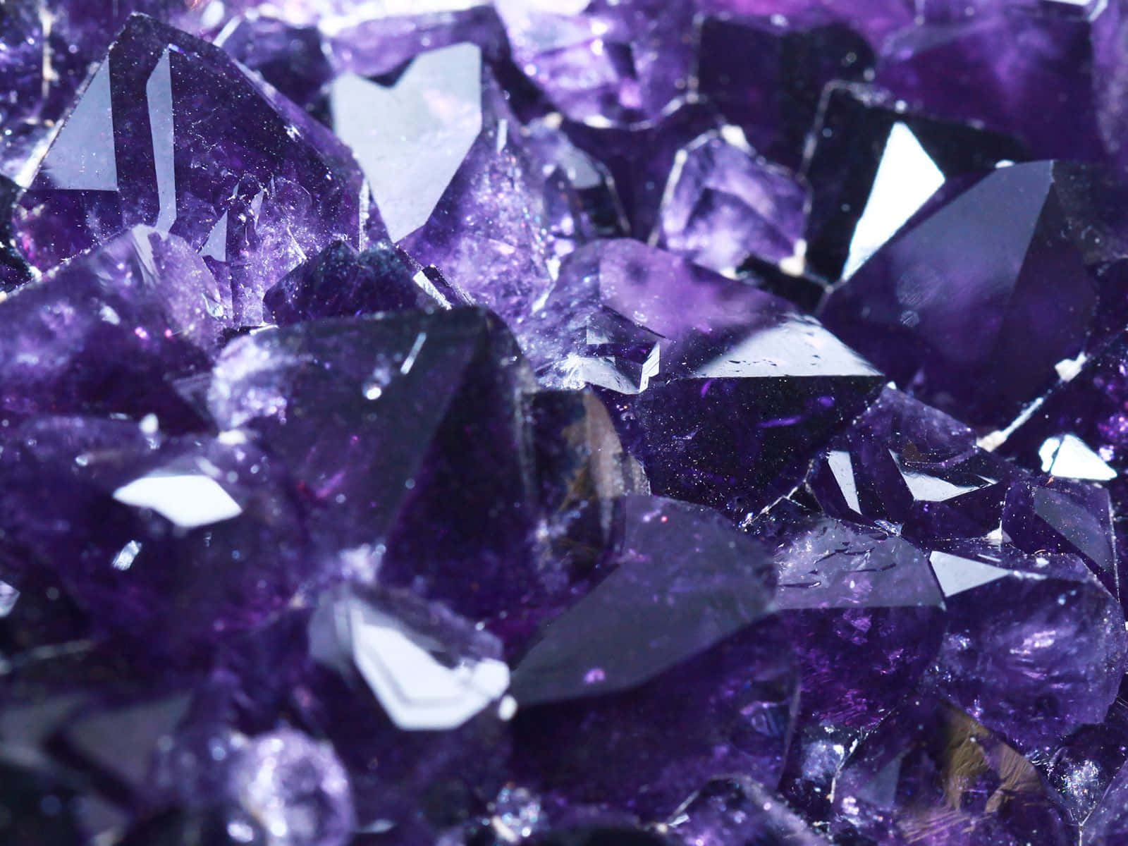Amethyst 桌布 壁紙 — 閃爍紫色紫水晶晶體的近距離特寫，具有鋒利的刻面，捕捉明亮光線。