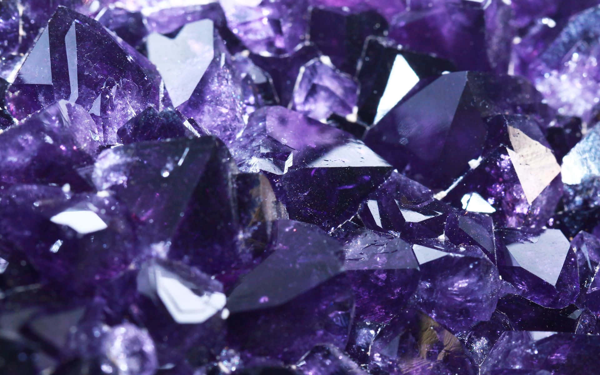 Amethyst 桌布 壁紙 — 閃爍紫色紫水晶晶體的近距離特寫，具有鋒利的刻面，捕捉明亮光線。