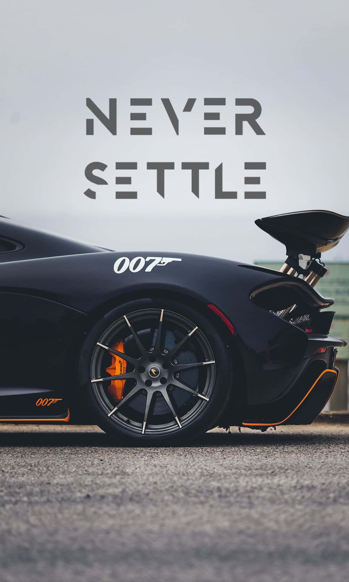 閃耀的藍色海洋映照晴空 壁紙 — 一輛時尚的黑色Aston Martin，帶有橙色制動卡鉗和「007」貼紙，停泊在陰天下的瀝青路面上。