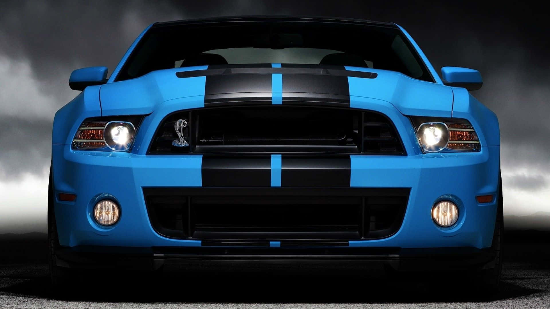 帶有黑色條紋的藍色Shelby Mustang，在暴風雨天空下。