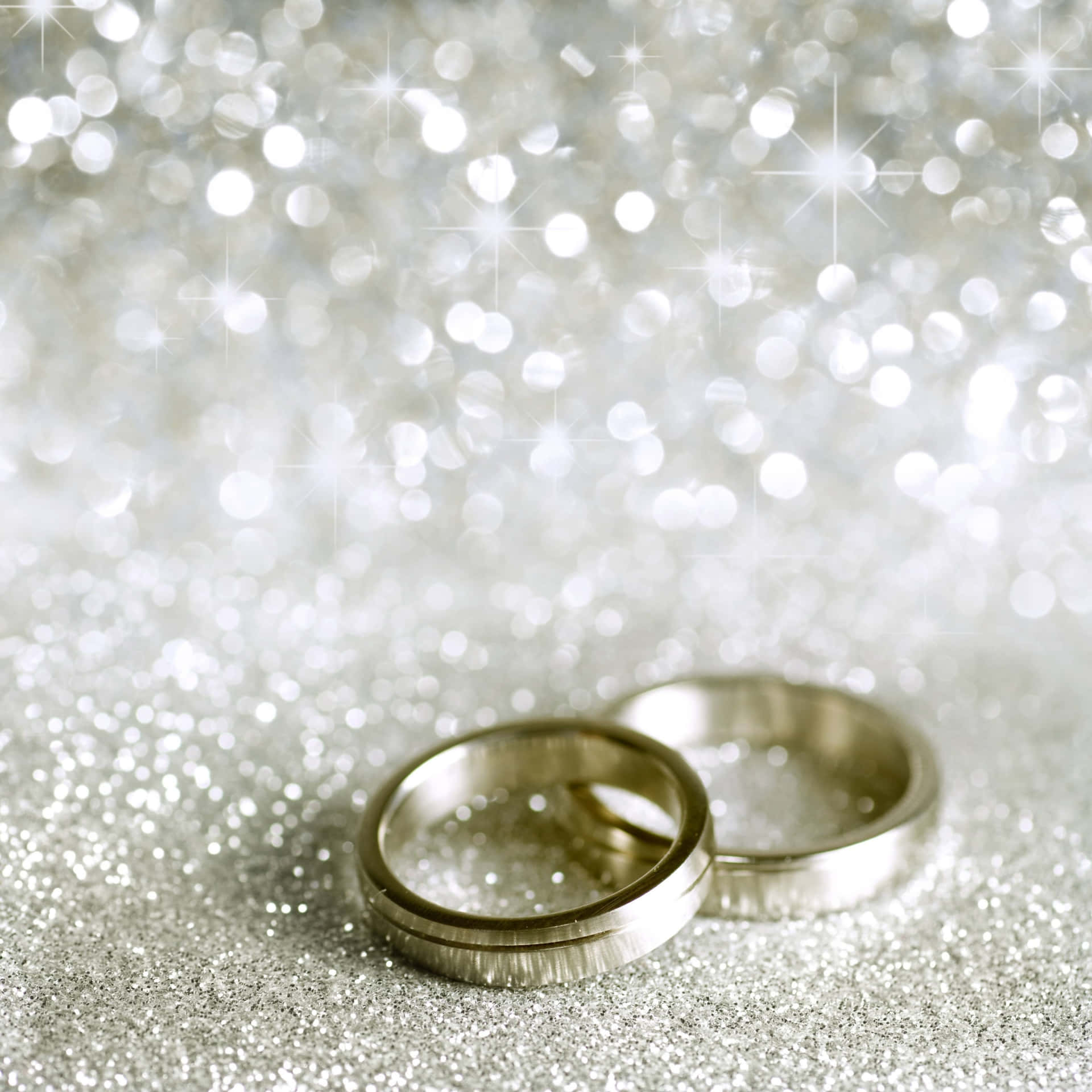 兩枚銀色結婚戒指在閃閃發光的銀色背景上。