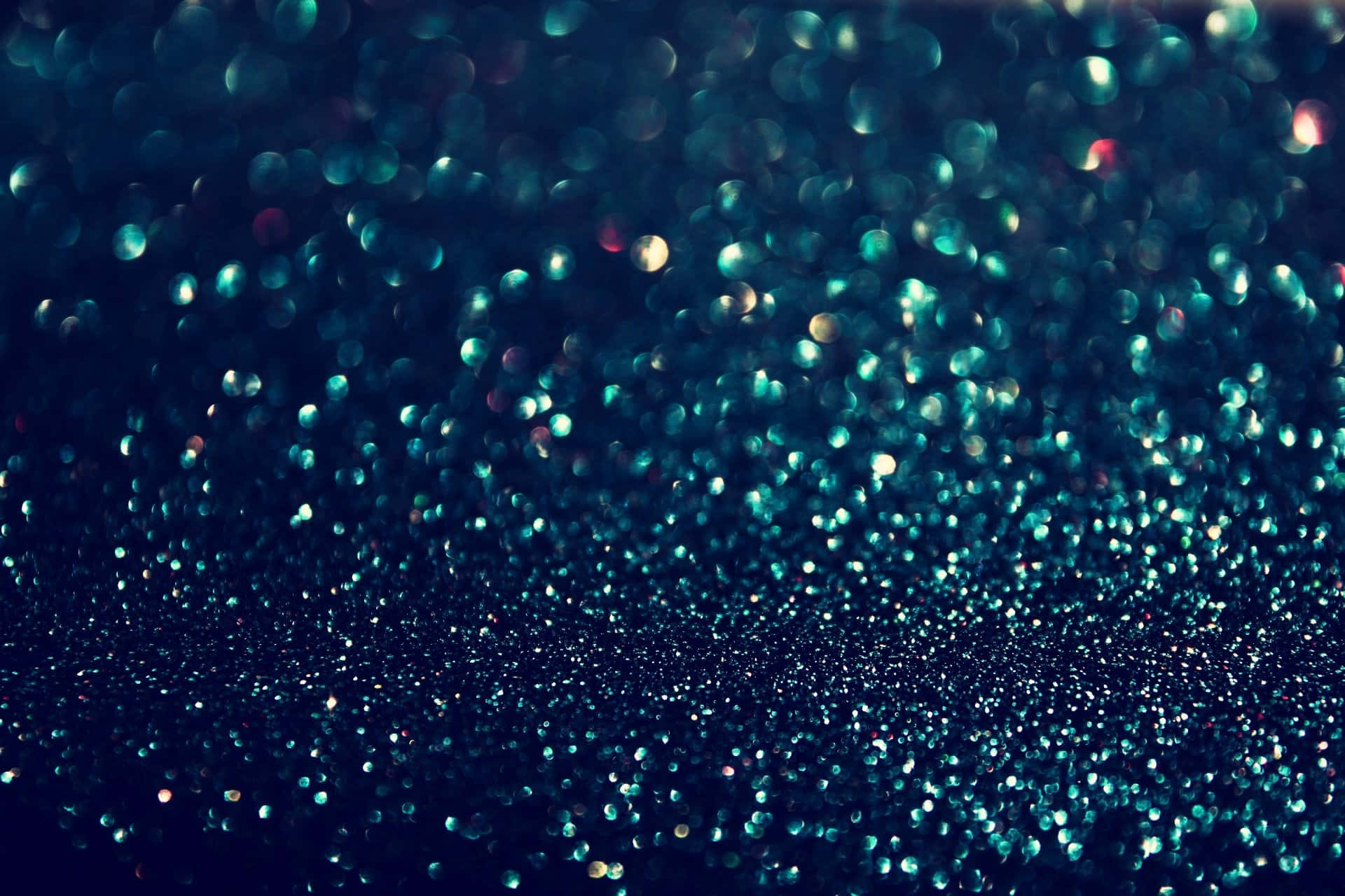 閃耀高解析度閃粉背景 壁紙 — 一個迷人的領域，由藍綠色和金色閃粉顆粒組成，在深藍色背景上柔和地模糊成夢幻般的散景。