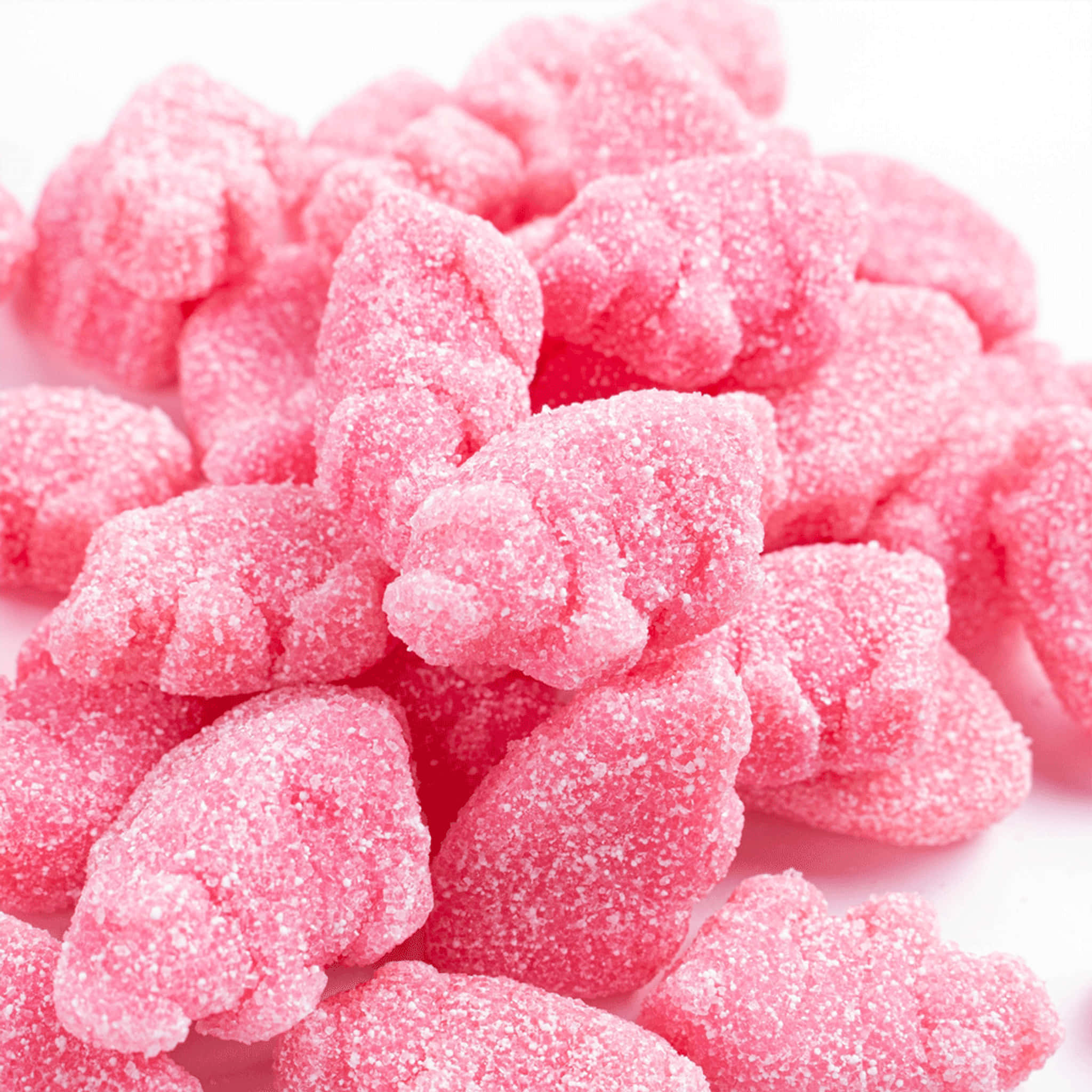 Pink Candy 桌布 壁紙 — 閃閃發光的粉紅色糖衣軟糖堆積在潔白背景上的特寫。