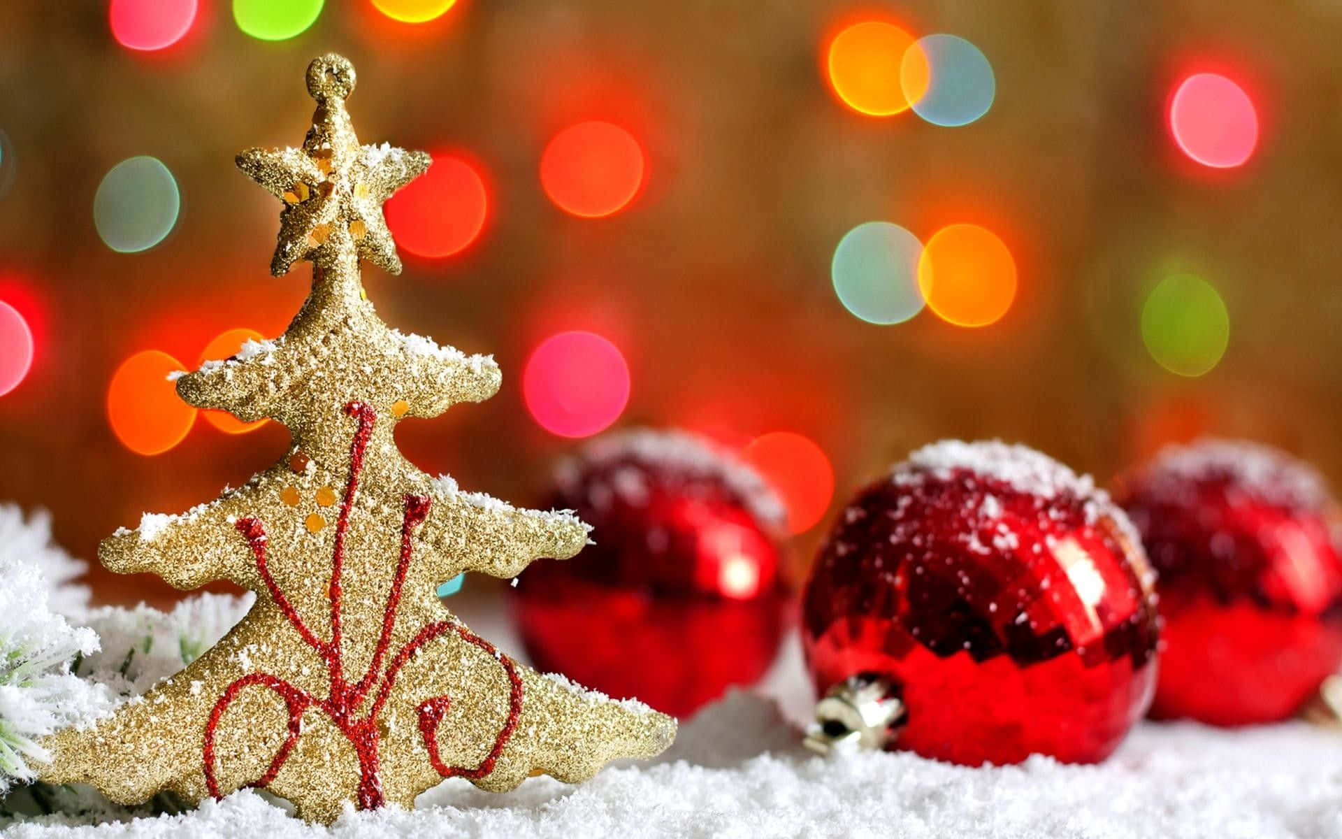 Winter Holiday 桌布 壁紙 — 閃閃發光的金色聖誕樹裝飾和灑滿雪的紅色飾球，放在白色雪地上，背景是色彩繽紛的散景燈光。