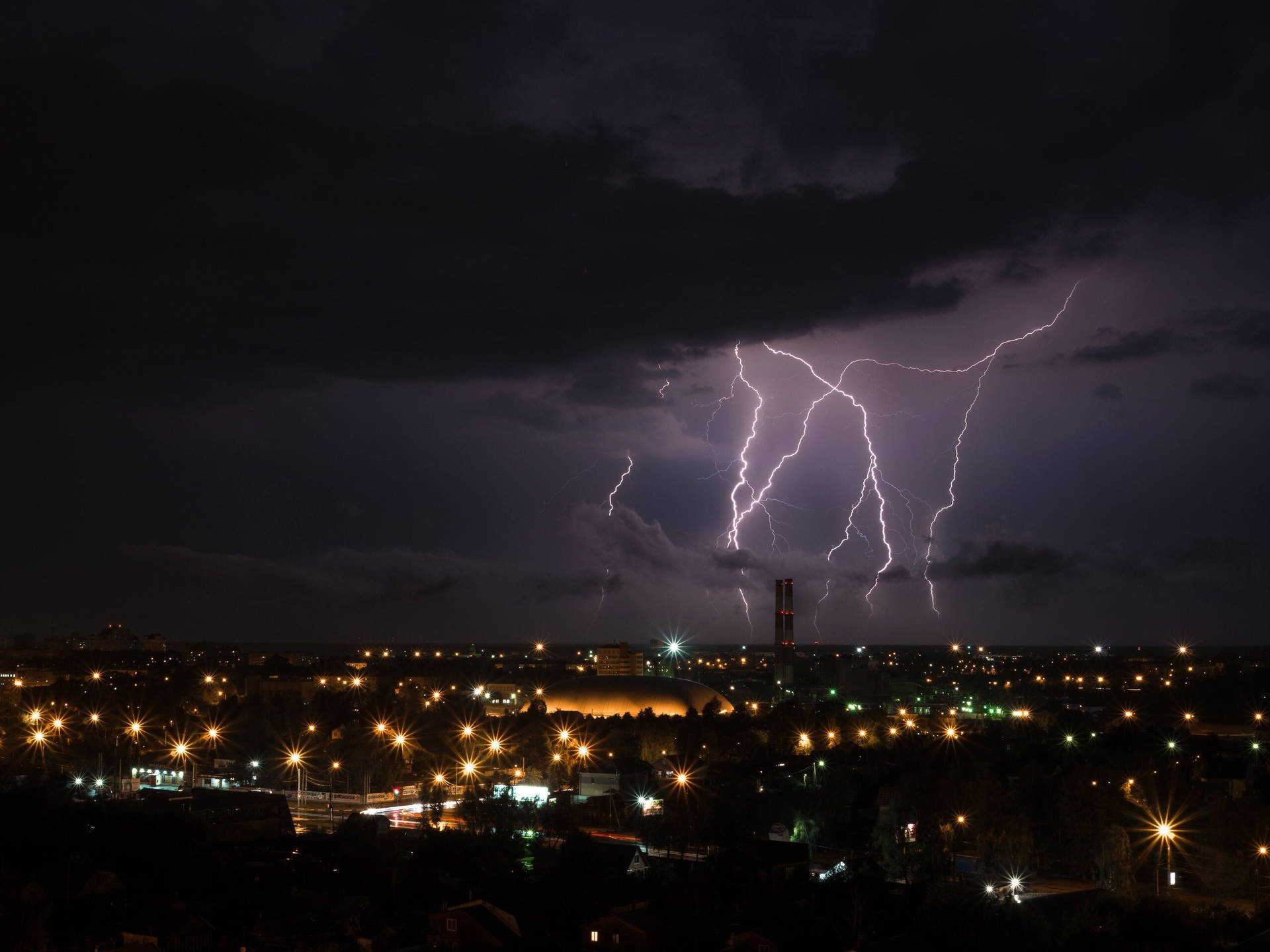 夜間城市上空的閃電，下方有發光的街燈。