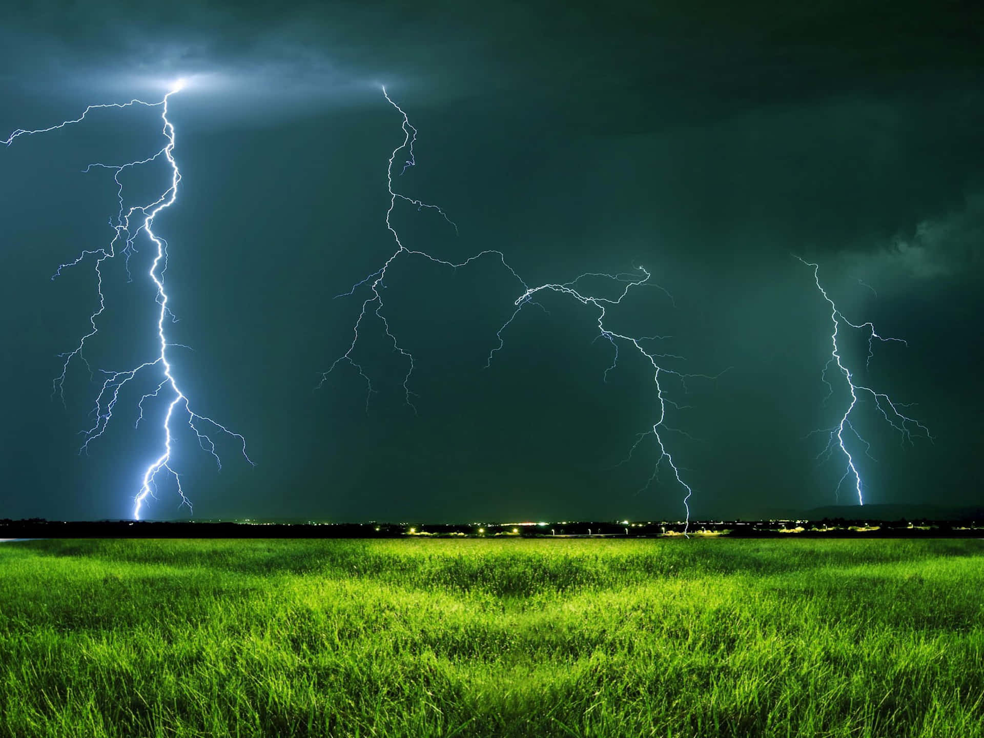 在暴風雨的夜空下，一片綠草地，有多道閃電。