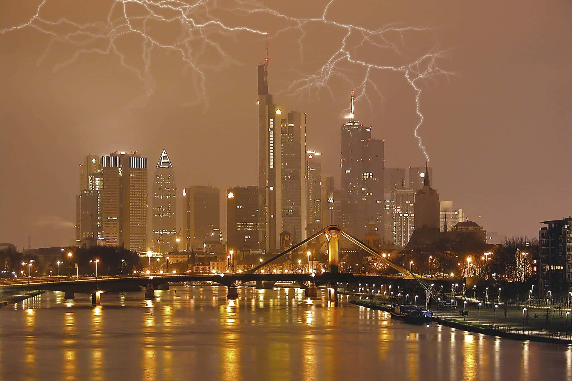 Germany 桌布 壁紙 — 閃電照亮現代城市天際線的夜晚，燈光倒映在下面的河流上。