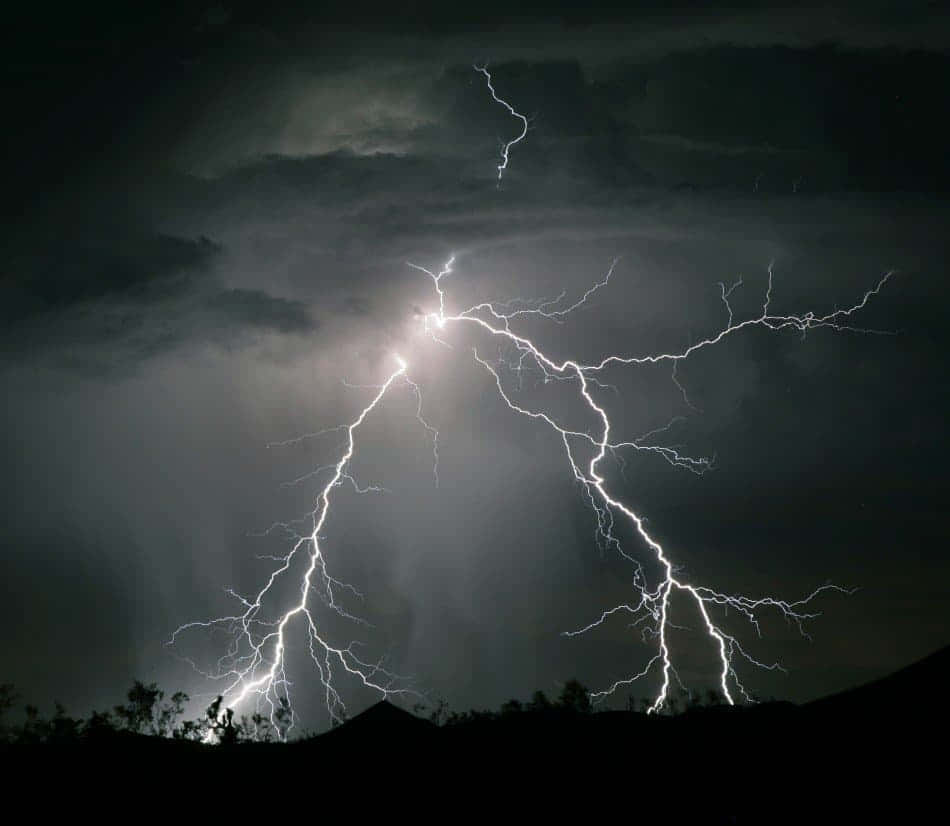 強烈的閃電照亮了黑暗山丘上方的暴風雨夜空。