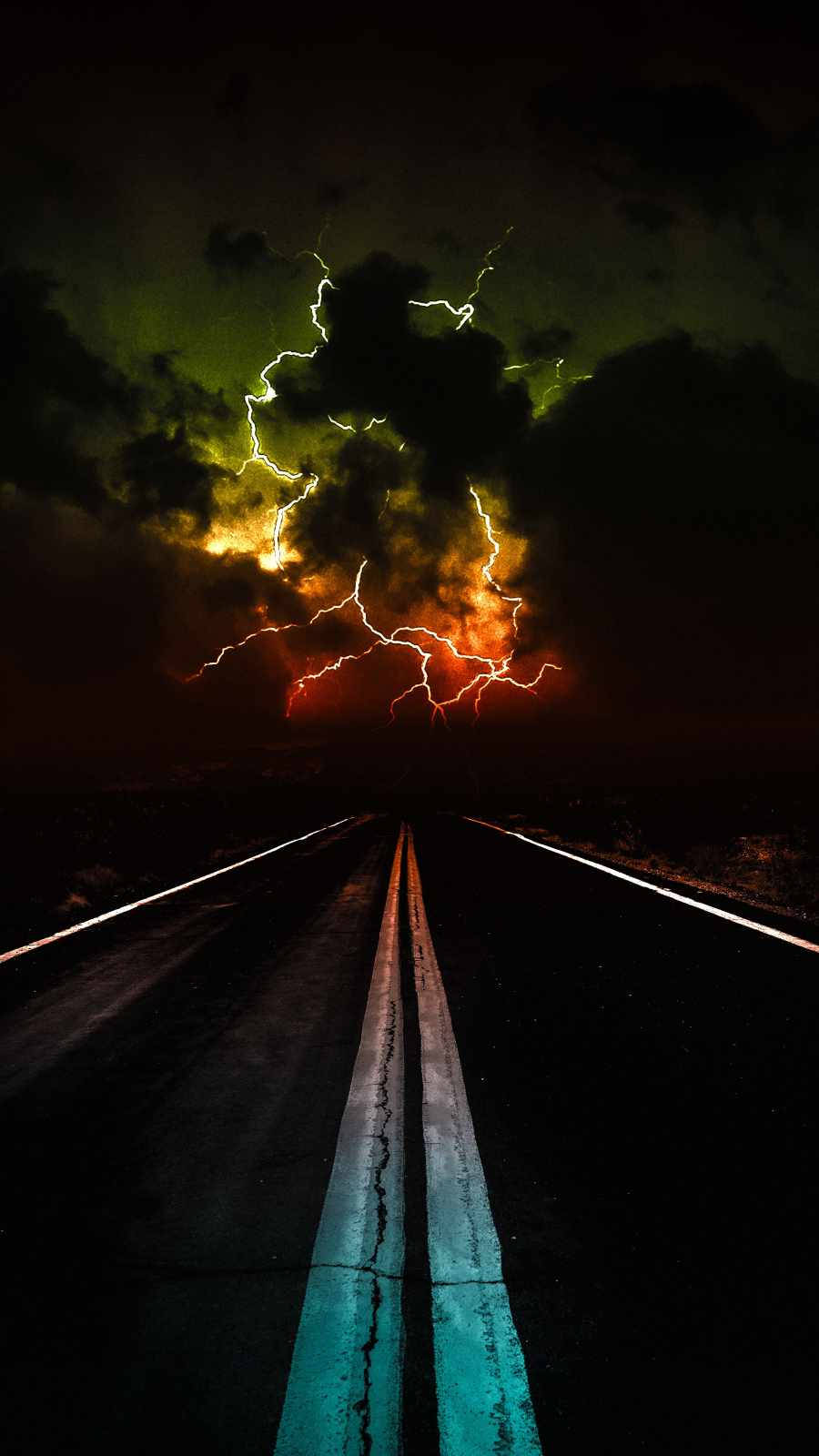 閃電與彩色雲朵 iPhone 深色壁紙 壁紙 — 一條荒涼的道路延伸向暴風雨的天空，天空中有鮮豔的橙色和綠色閃電，構成戲劇性的夜景。