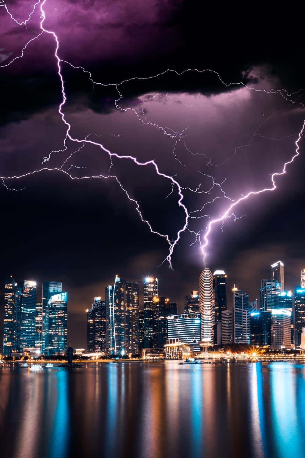 紫色閃電照亮了倒映在水中的現代城市夜景天際線。