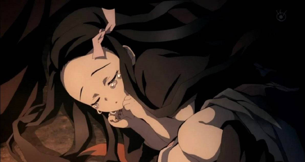 閉眼哭泣的鬼滅之刃禰豆子 壁紙 — 一位年輕的動漫女孩，深色頭髮，淚眼汪汪，在昏暗的場景中將頭靠在手上。
