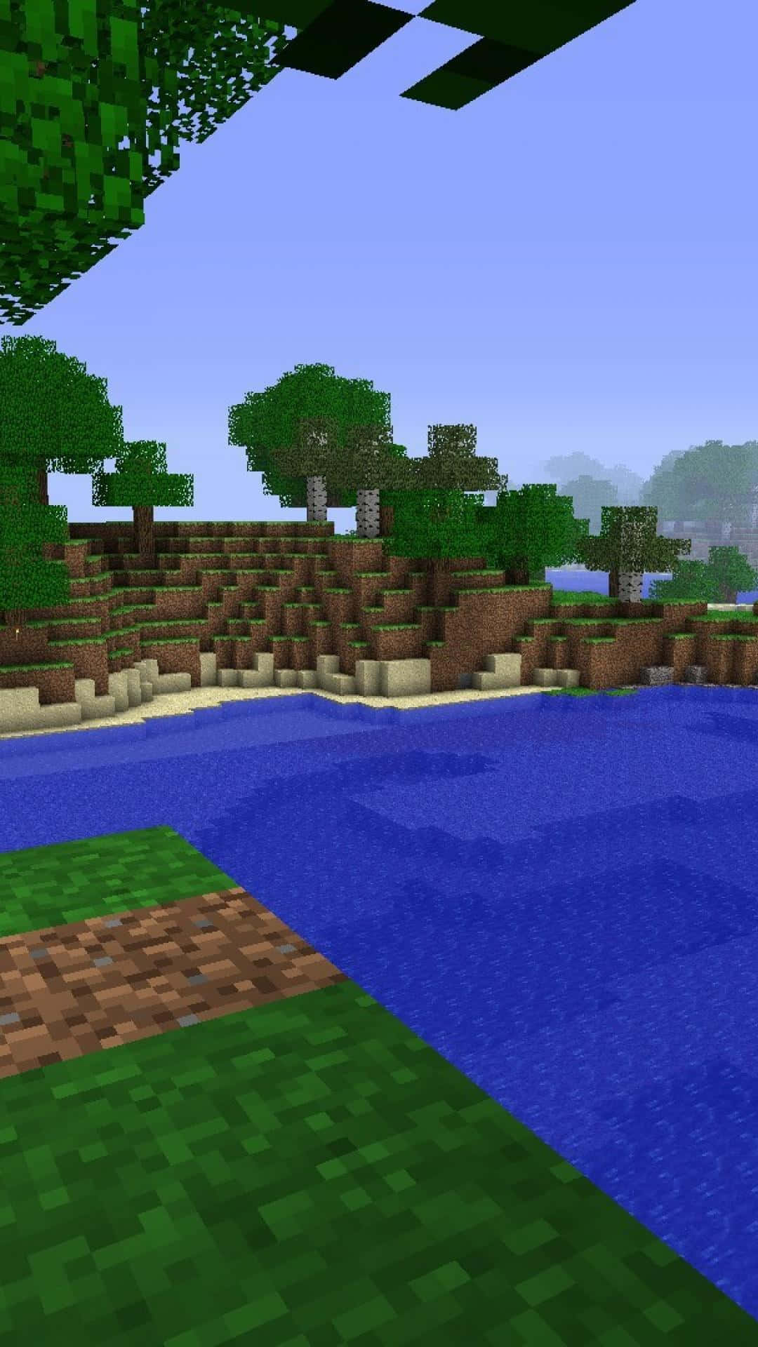 開放世界像素3 Minecraft背景 壁紙 — 一個像素化的Minecraft景觀，藍色河流流過綠色草地和棕色泥土山丘，有方塊狀的樹木，天空晴朗。
