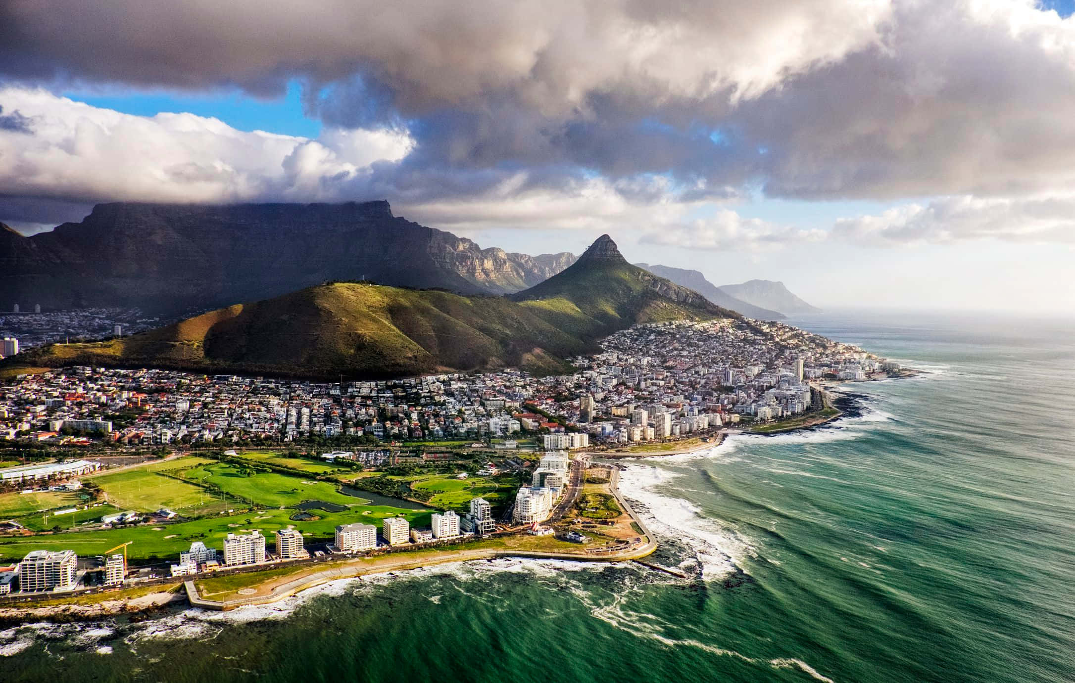 South Africa 桌布 壁紙 — 開普敦的鳥瞰圖，桌山聳立在沿海城市景觀之上，下方是碧綠的海浪拍打。