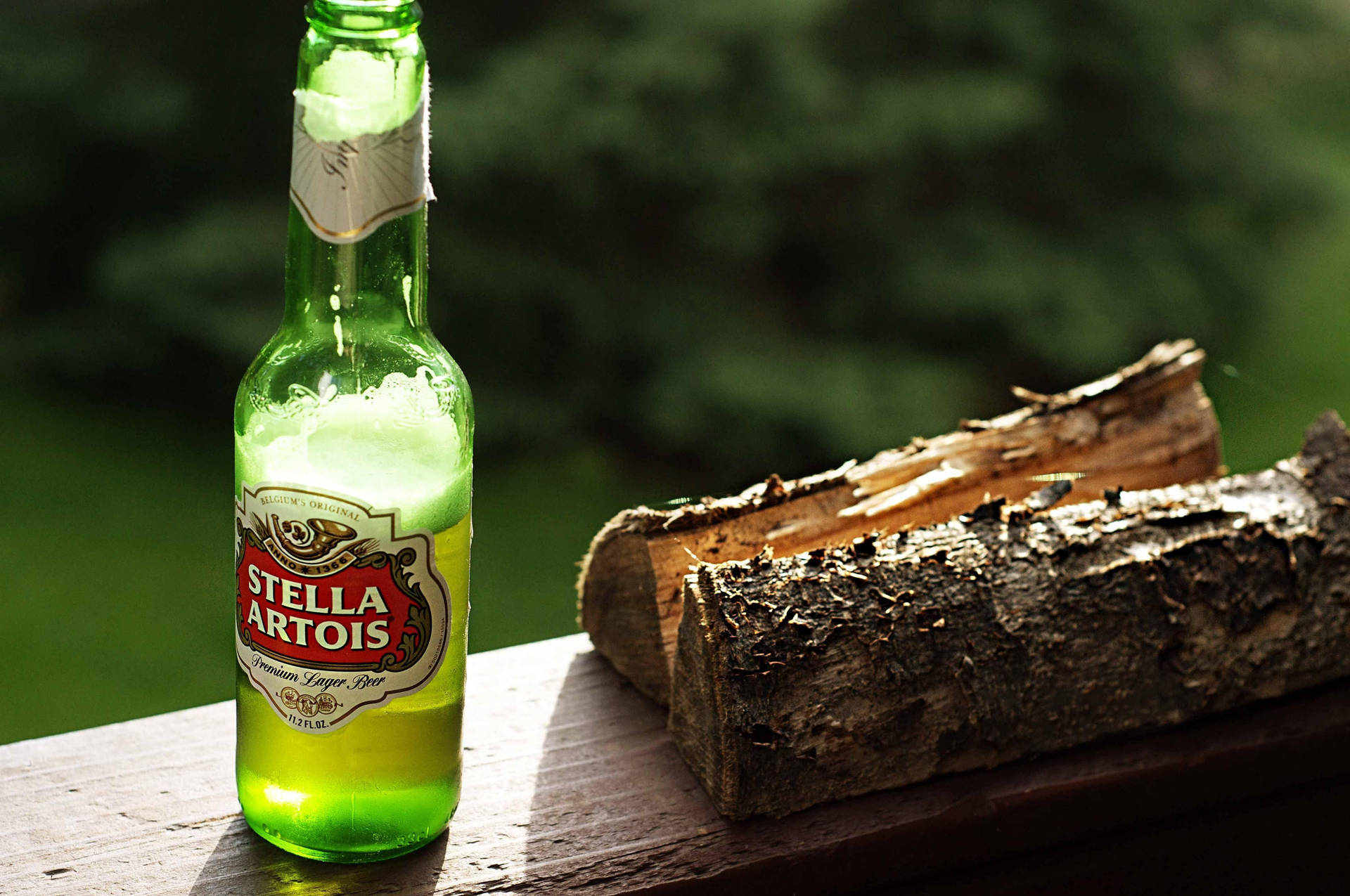 冰凍的 Stella Artois 啤酒瓶放在森林環境中的木甲板上，旁邊是柴火。