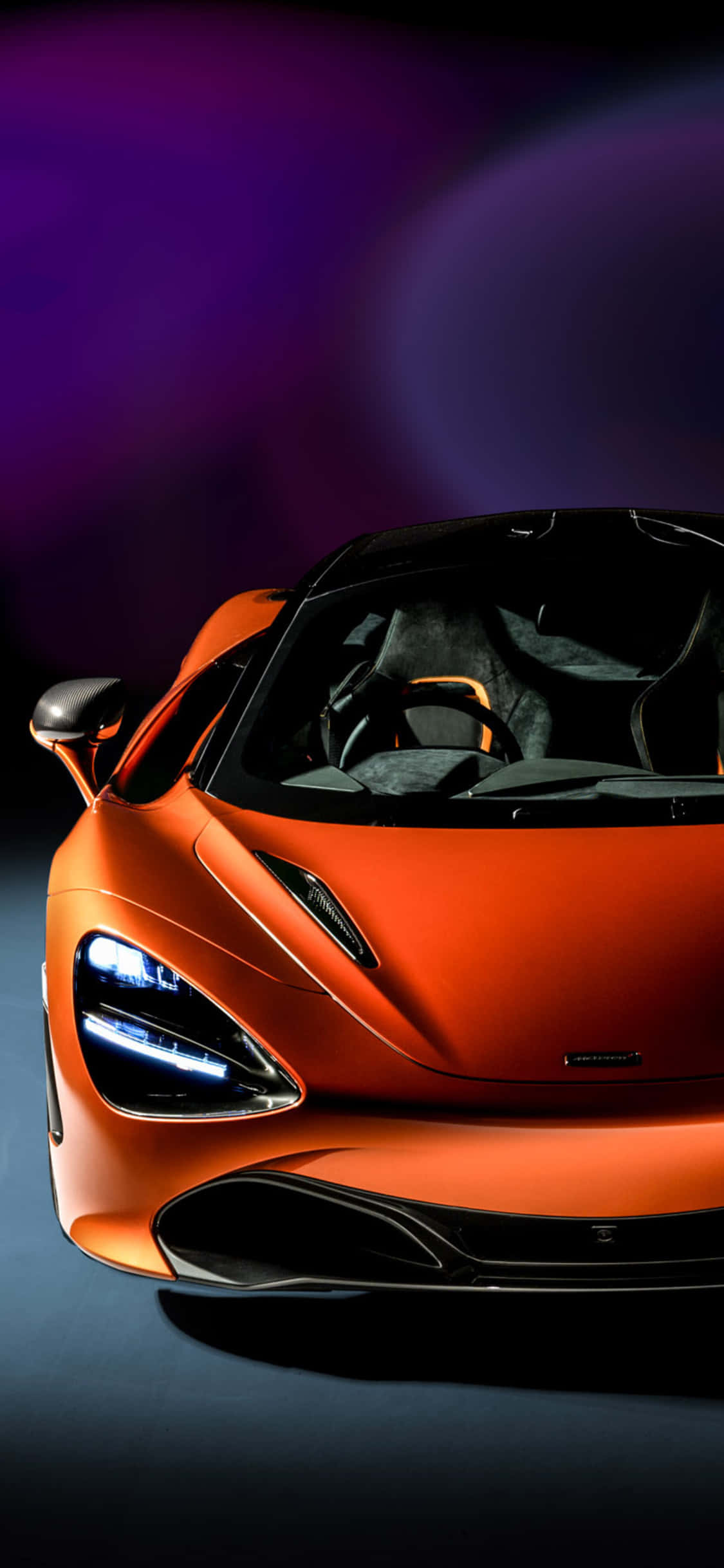 關於 Project Cars 2 與 iPhone XS Max 的所有資訊 壁紙 — 一輛時尚的橙色McLaren跑車，配以發光的車頭燈，在充滿活力的紫色和藍色漸變背景上展示。