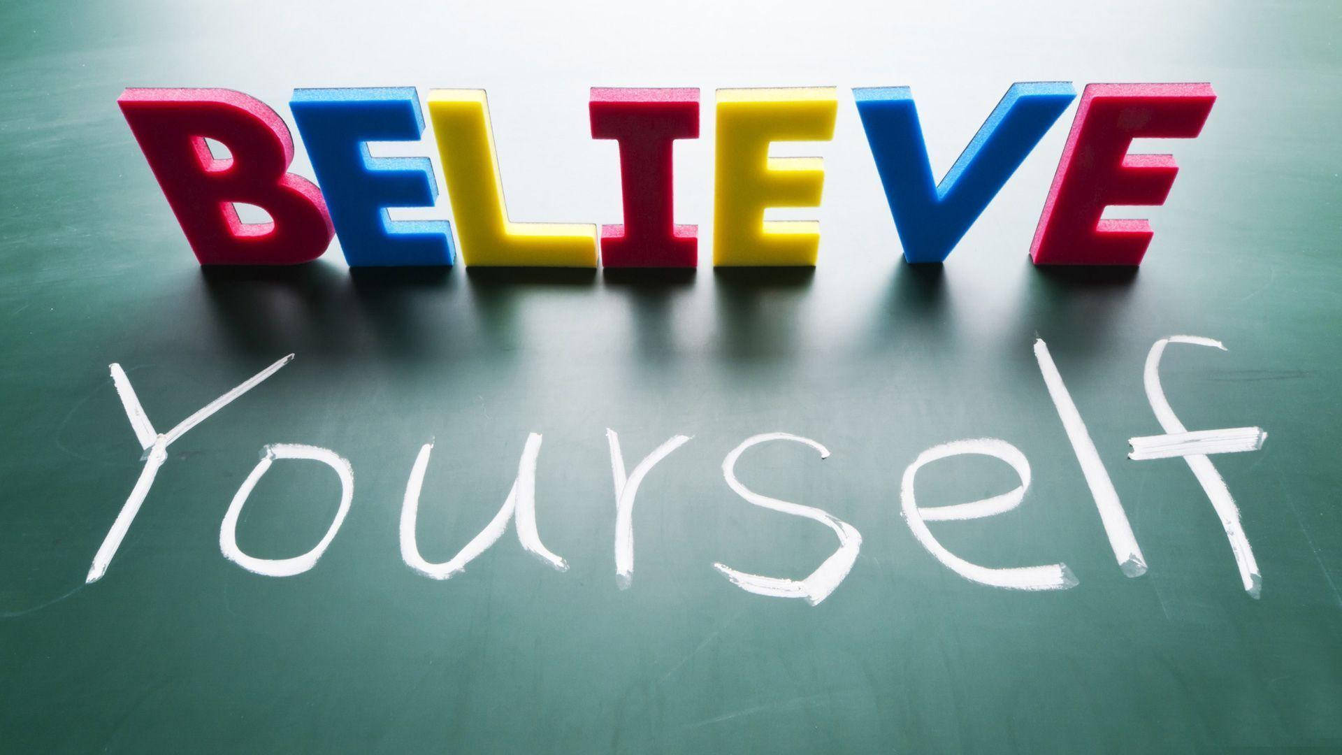 色彩繽紛的3D字母拼出BELIEVE，放在一塊用粉筆寫着'Yourself'的黑板上。