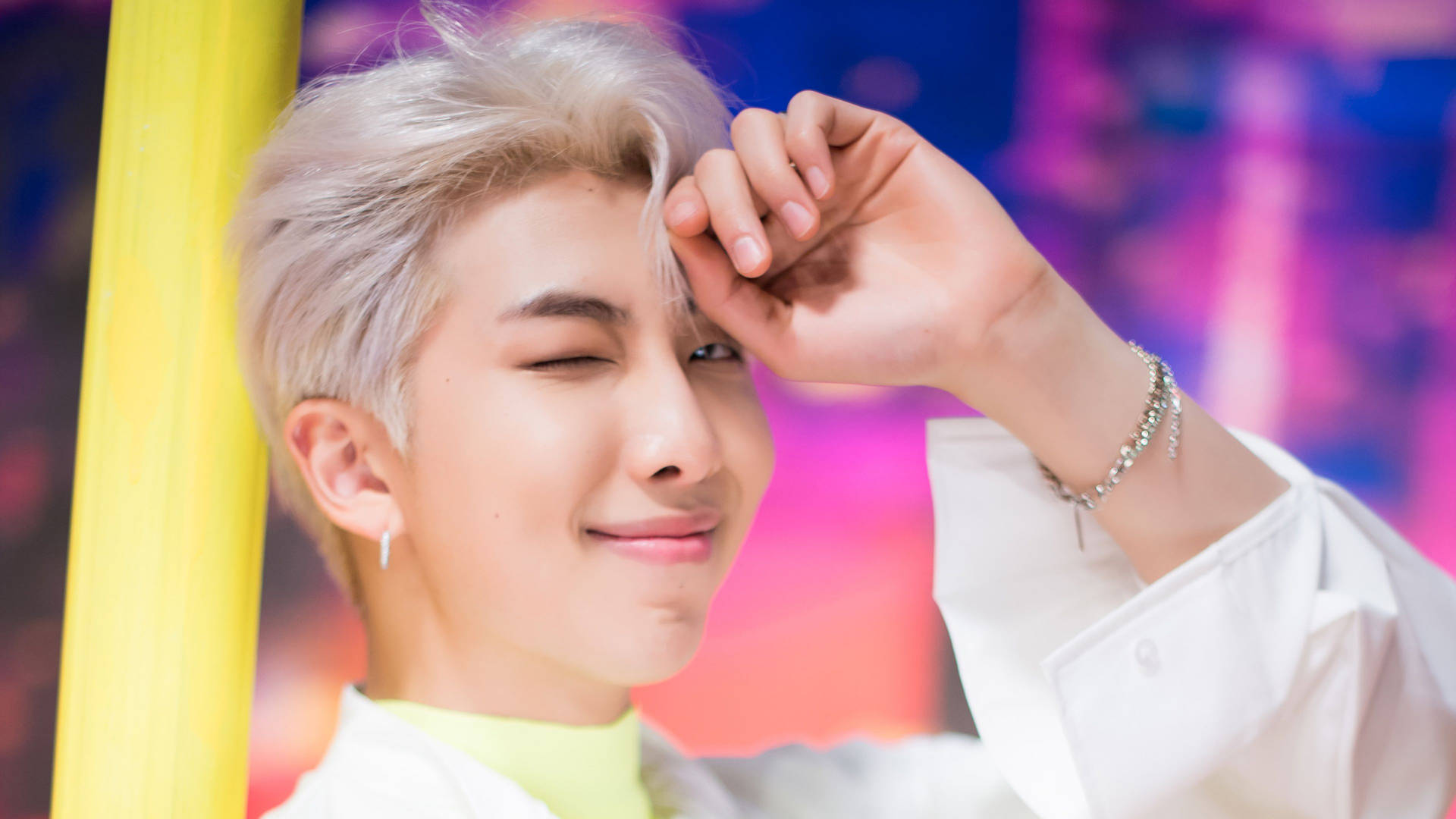 RM BTS《Boy With Luv》歌曲 壁紙 — 一位銀髮年輕男子在充滿活力的霓虹背景前，調皮地眨眼並觸碰額頭。
